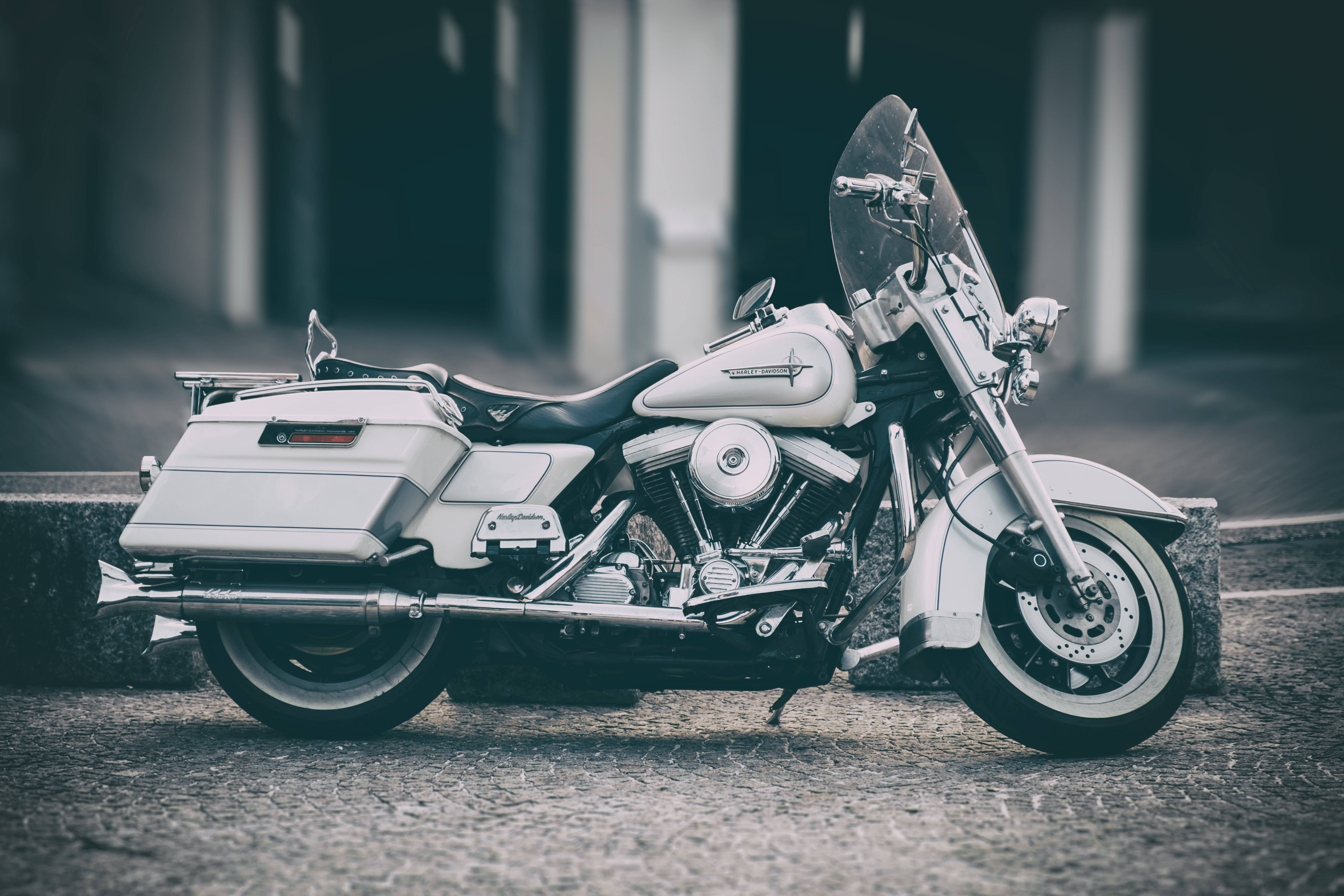 Harley 桌布 壁紙 — 一架時尚的白色巡航機車，帶有鍍鉻裝飾，停在鵝卵石街道上，柔和日光下。