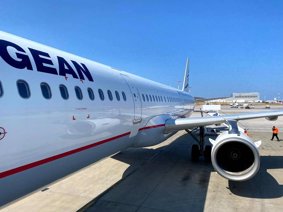Airport 桌布 壁紙 — 一架時尚的白色愛琴海航空飛機停在陽光明媚的停機坪上，藍天清澈，地勤人員在附近。