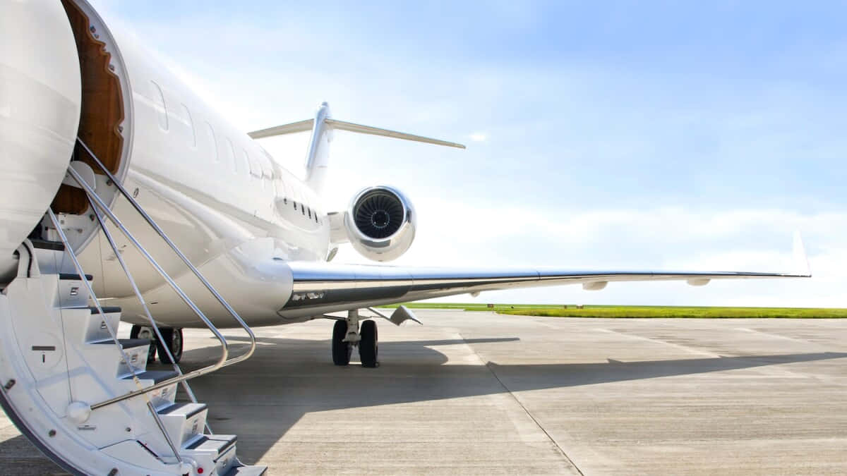 flying 桌布 壁紙 — 一架時尚的白色私人飛機停在陽光明媚的停機坪上，艙門打開，樓梯伸出，背景是清澈的藍天。