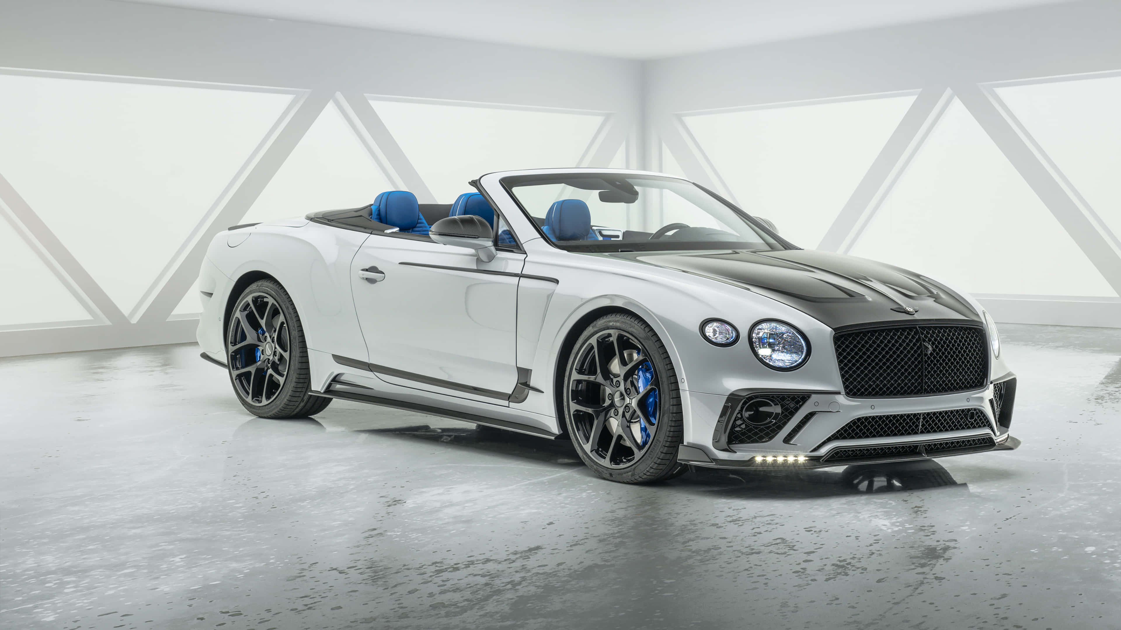 Bentley Continental Gt 桌布 壁紙 — 一架時尚的白色賓利敞篷車，配備藍色內裝和黑色飾邊，在簡約的白色幾何工作室中展示。