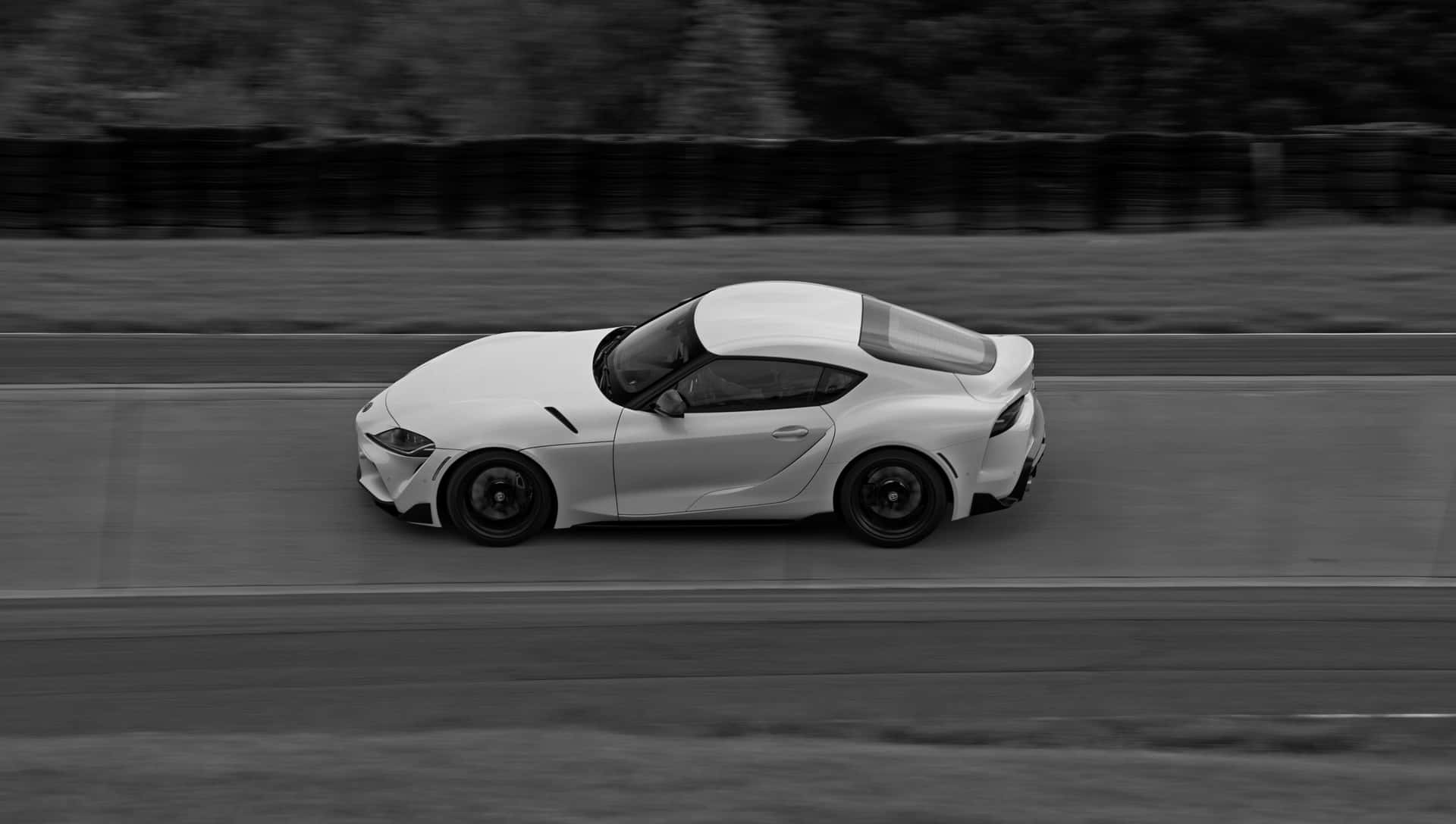 白色跑車在賽道上以動態模糊效果疾馳。 — Toyota Supra Mk4 壁紙