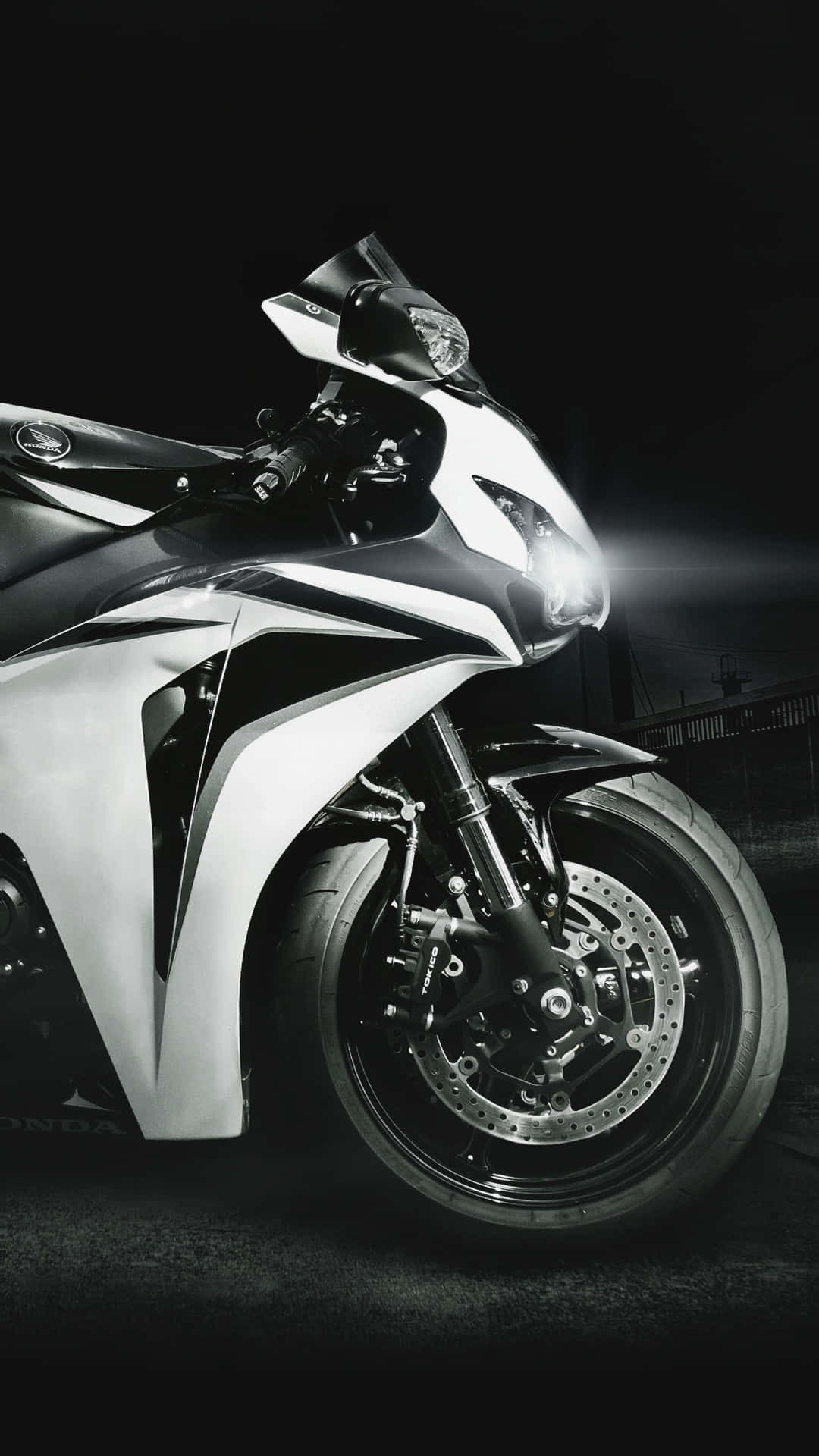 Superbike 桌布 壁紙 — 一架時尚的白色運動機車，帶有發光的頭燈，主宰著黑暗的城市夜景。