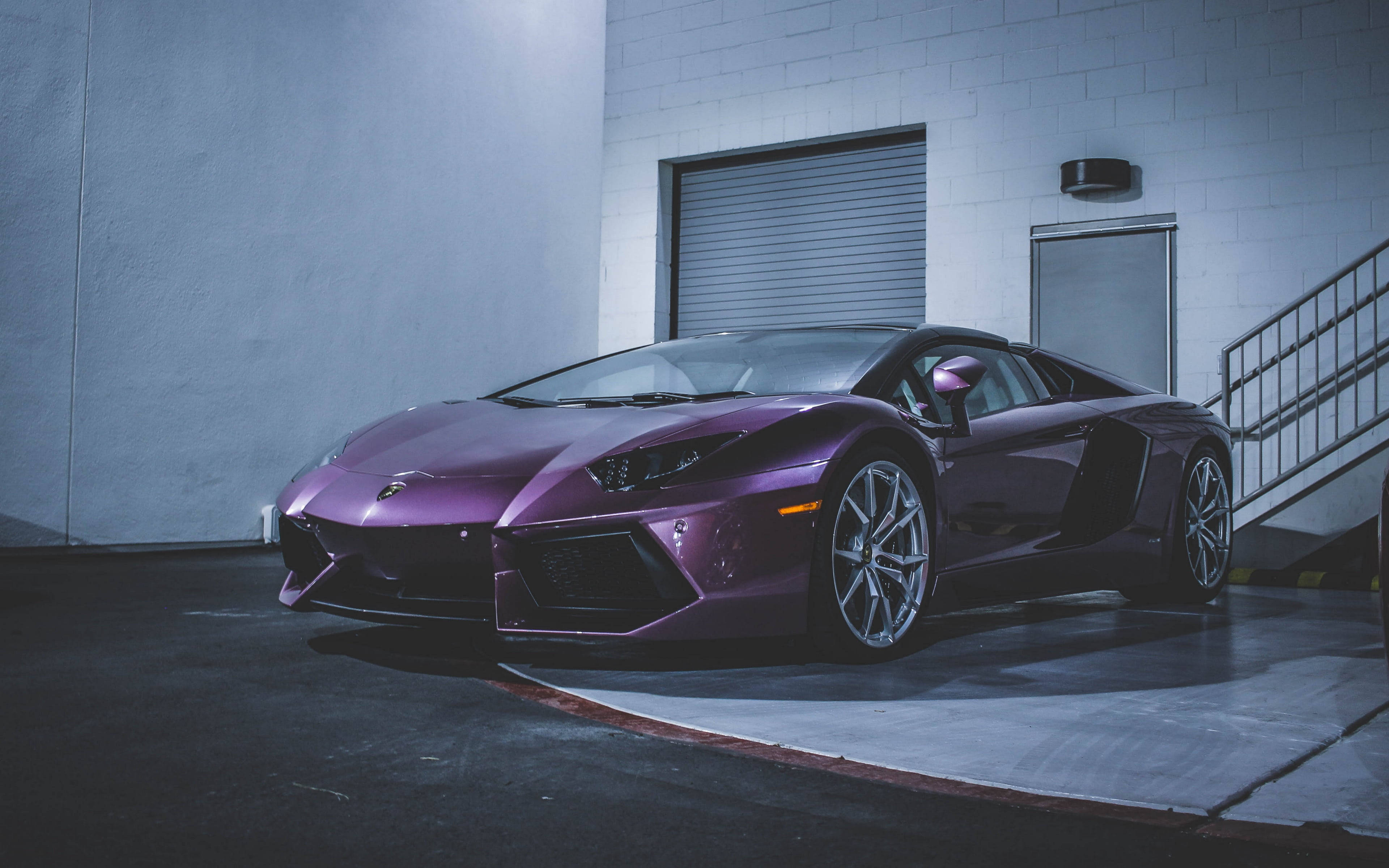 跑車 桌布 壁紙 — 一架時尚的紫色藍寶堅尼Aventador停放在光線昏暗的工業車庫，內有混凝土牆和金屬樓梯。