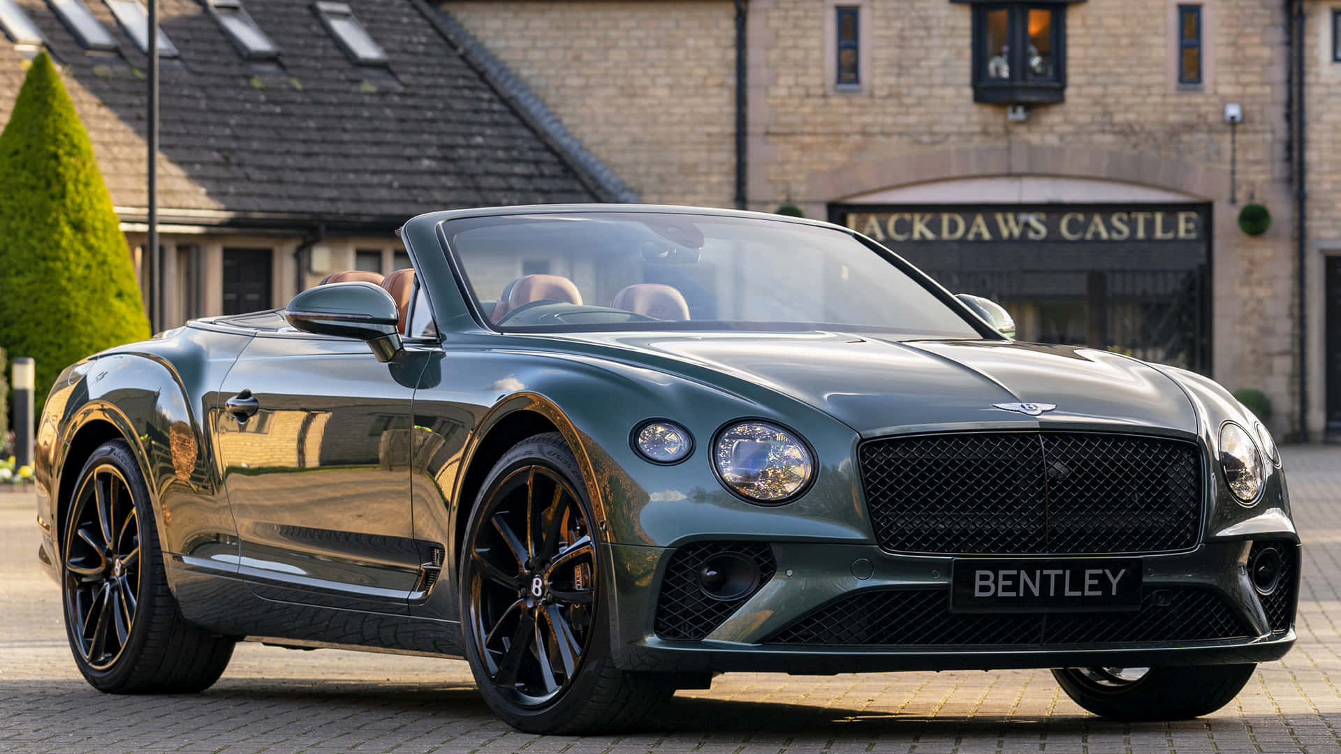 Bentley Continental Gt Convertible 桌布 壁紙 — 一架時尚的綠色賓利敞篷車停泊在傑克道斯城堡前的鵝卵石車道上，陽光在其拋光表面上反射。