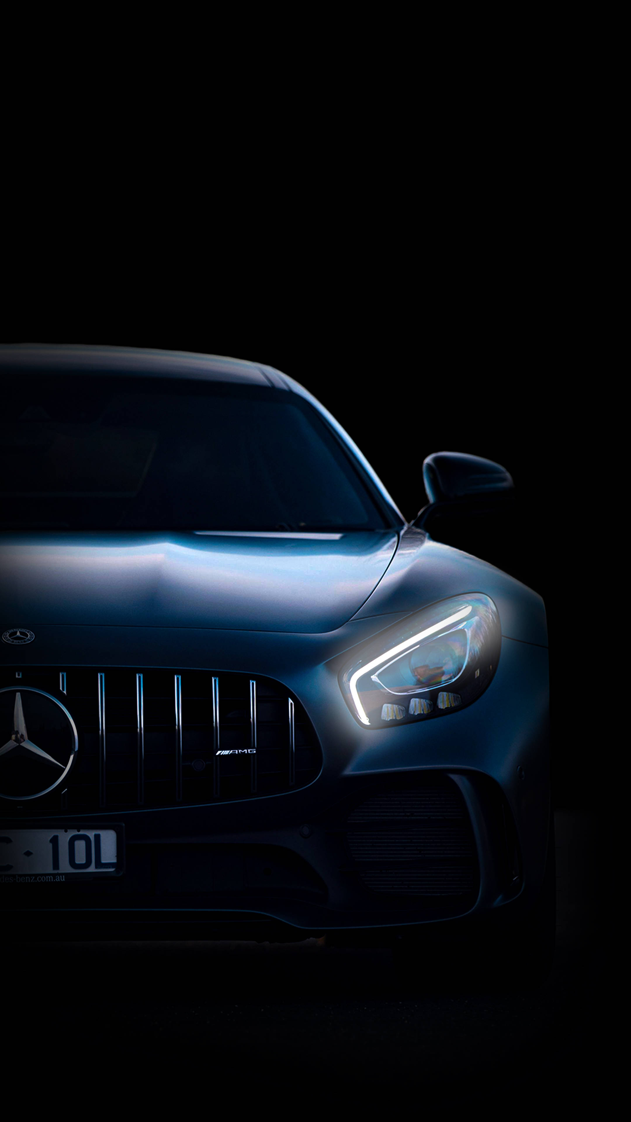 iPhone 桌布 壁紙 — 一架時尚的藍色 Mercedes-AMG 跑車在漆黑背景中閃爍著銳利的車頭燈。