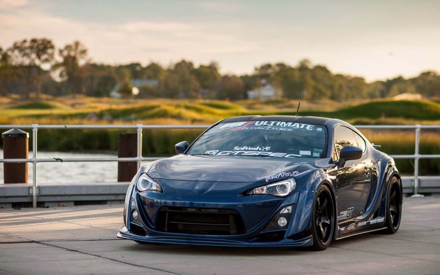 藍色改裝跑車停在海濱碼頭上，背景是高爾夫球場。 — Toyota Supra Mk4 壁紙