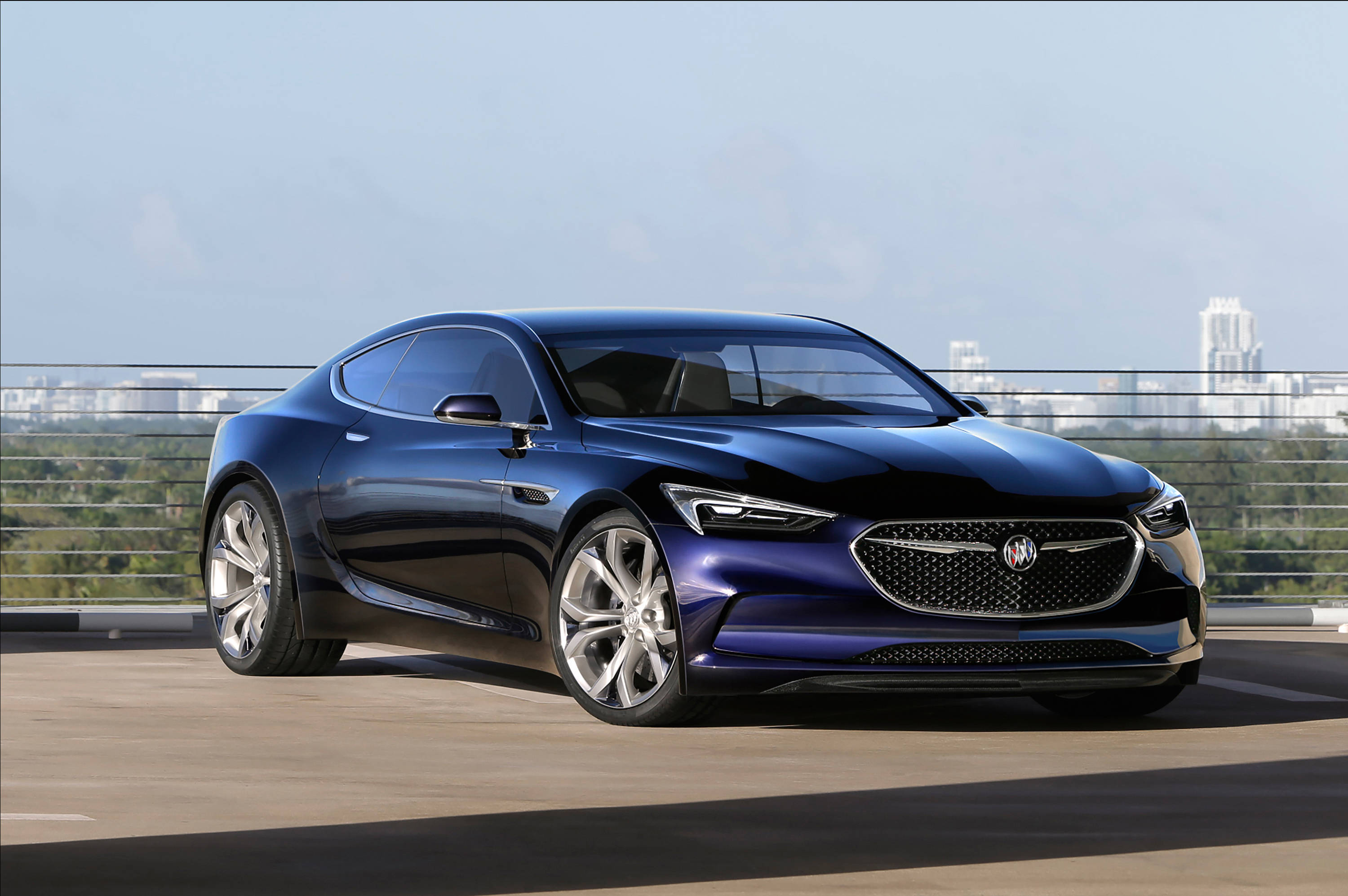 Buick 桌布 壁紙 — 一架時尚的藍色概念車在日光下閃耀，停泊在可俯瞰遠方城市景觀的屋頂上。