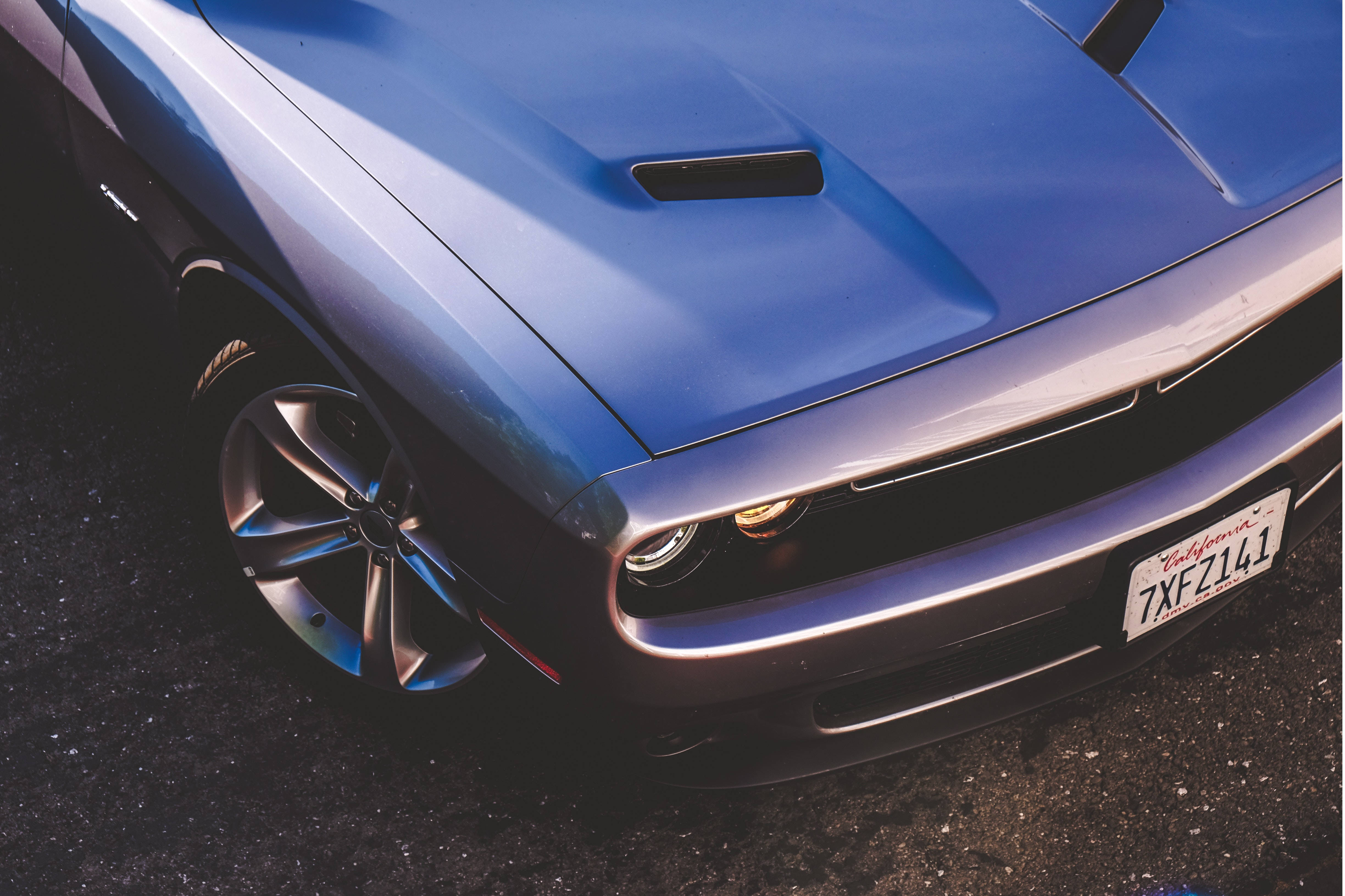 Cool Car 桌布 壁紙 — 一架時尚的藍色肌肉車，帶有引擎蓋進氣口和加州車牌，在溫暖的燈光下停在瀝青路上。