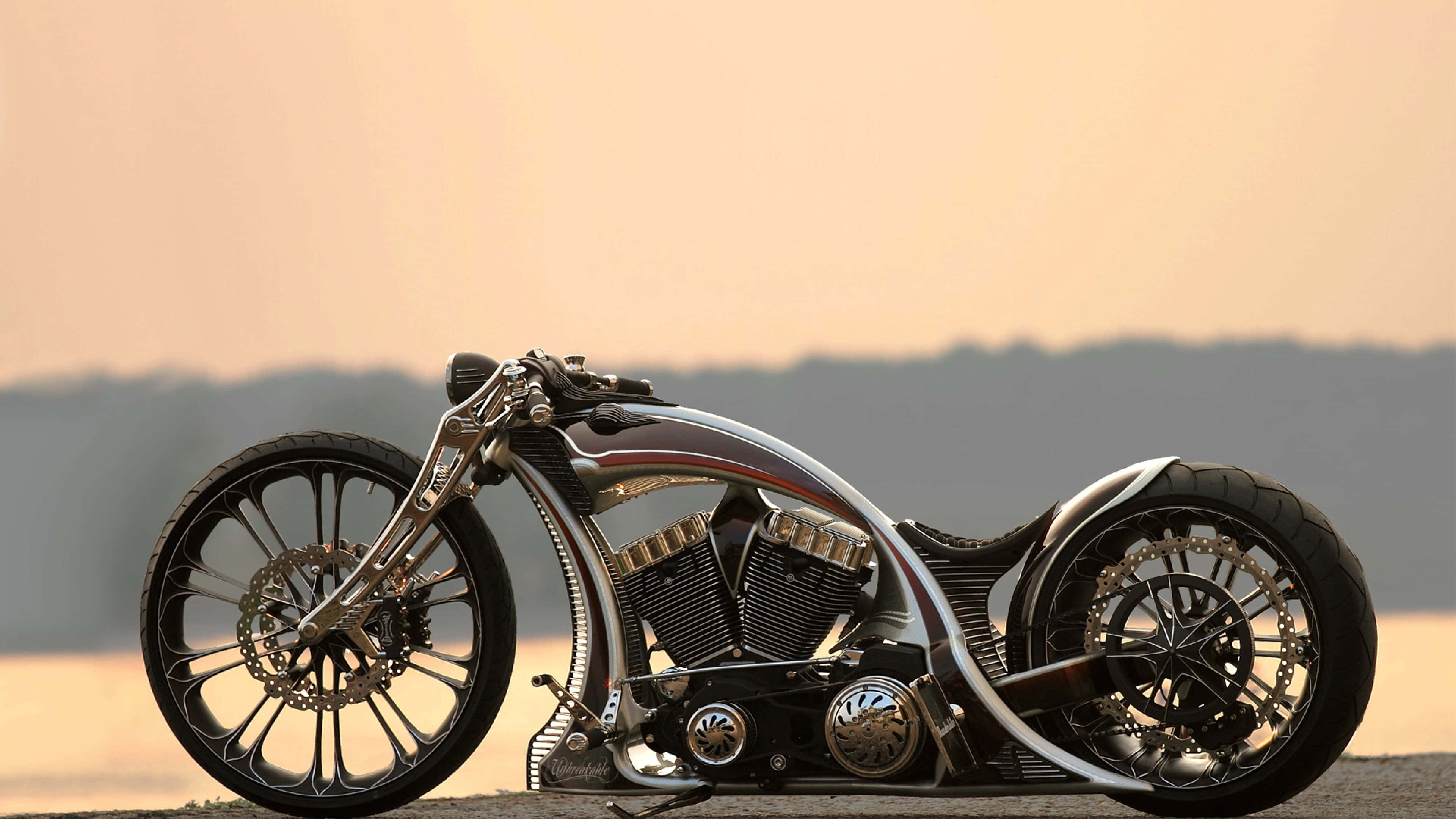 4K Bikes 桌布 壁紙 — 一架時尚的訂製chopper機車，帶有鍍鉻裝飾和鋼絲輪圈，在日落時停放在鋪砌路面上。