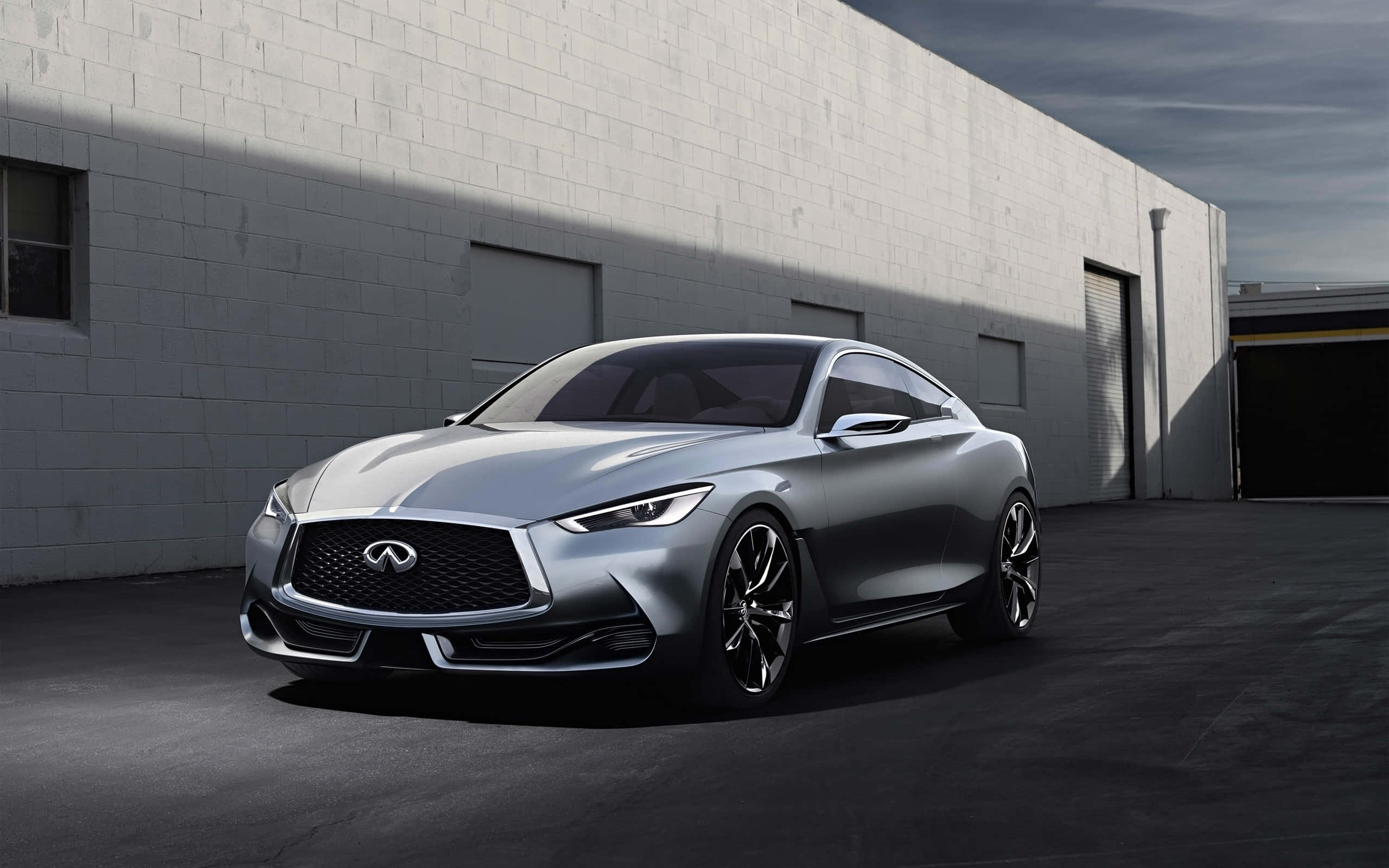 Infiniti Q60 桌布 壁紙 — 一架時尚的銀色 Infiniti 跑車停放在純白色磚造倉庫前，燈光效果極具戲劇性。