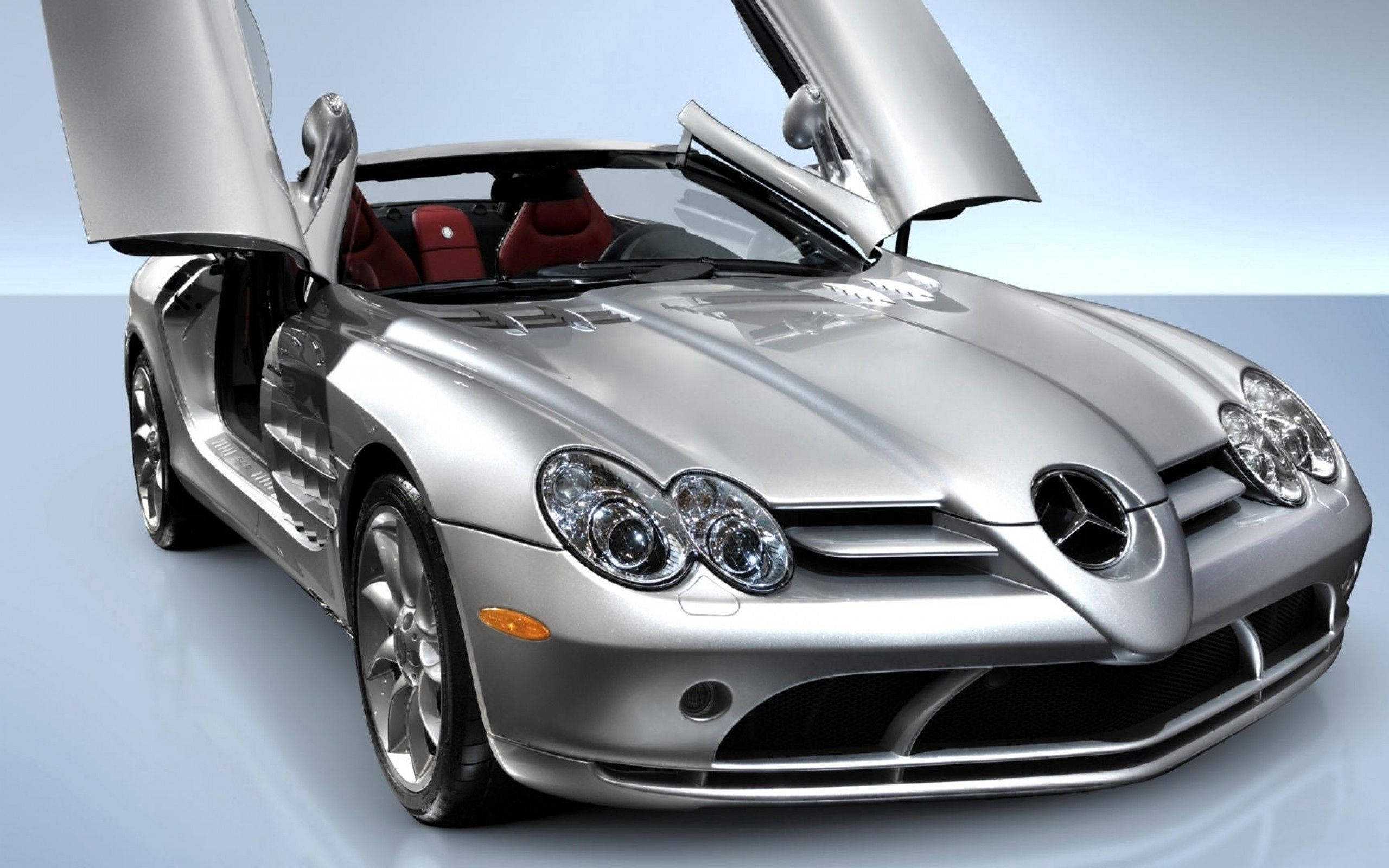 跑車 桌布 壁紙 — 一架時尚的銀色 Mercedes SLR McLaren 跑車，鷗翼門打開，背景是簡約的淺藍色工作室。