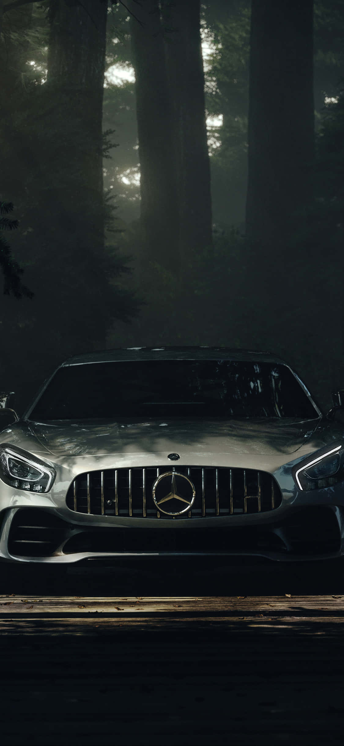 iPhone X Amg Gt-r 桌布 壁紙 — 一架時尚的銀色 Mercedes-AMG GT 停泊在森林小徑上，周圍有霧氣繚繞的樹木，斑駁的光線穿過樹冠灑落。