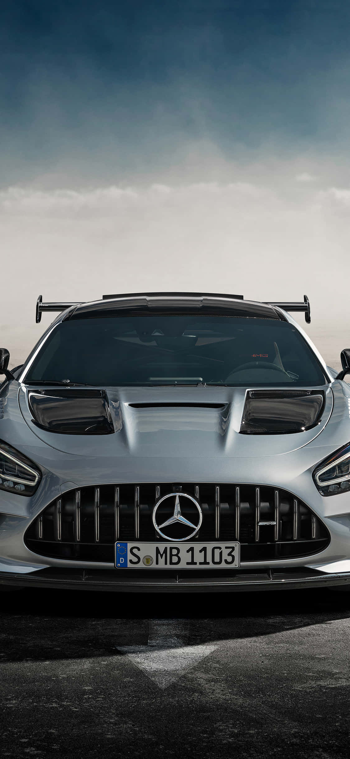 跑車 桌布 壁紙 — 一架時尚的銀色 Mercedes-AMG GT R 跑車在戲劇性的多雲天空下，在潮濕的瀝青路上向前行駛。
