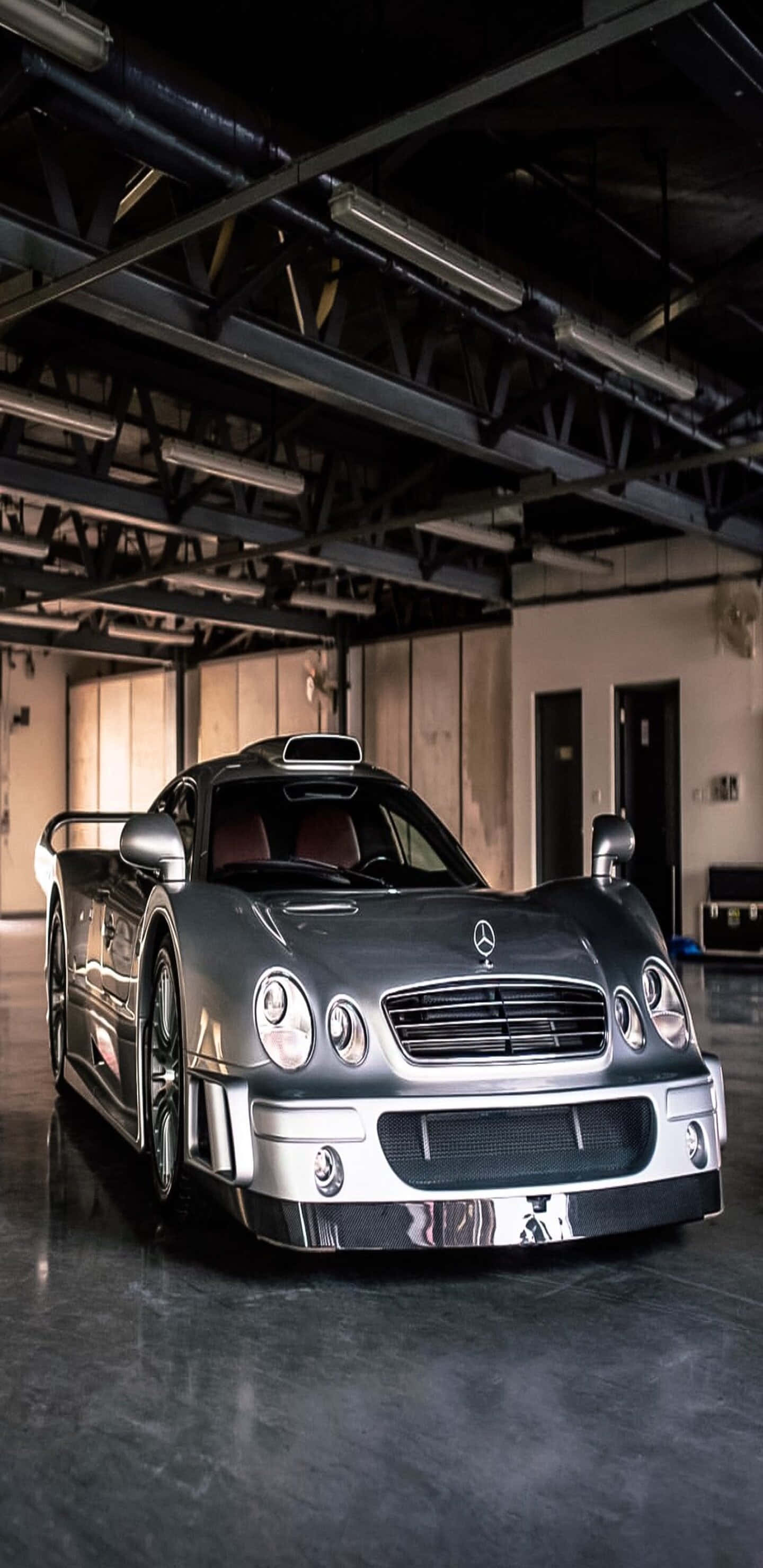 酷車 桌布 壁紙 — 一架時尚的銀色 Mercedes-Benz CLK GTR 跑車在寬敞的混凝土車庫中，在工業照明下閃閃發光。