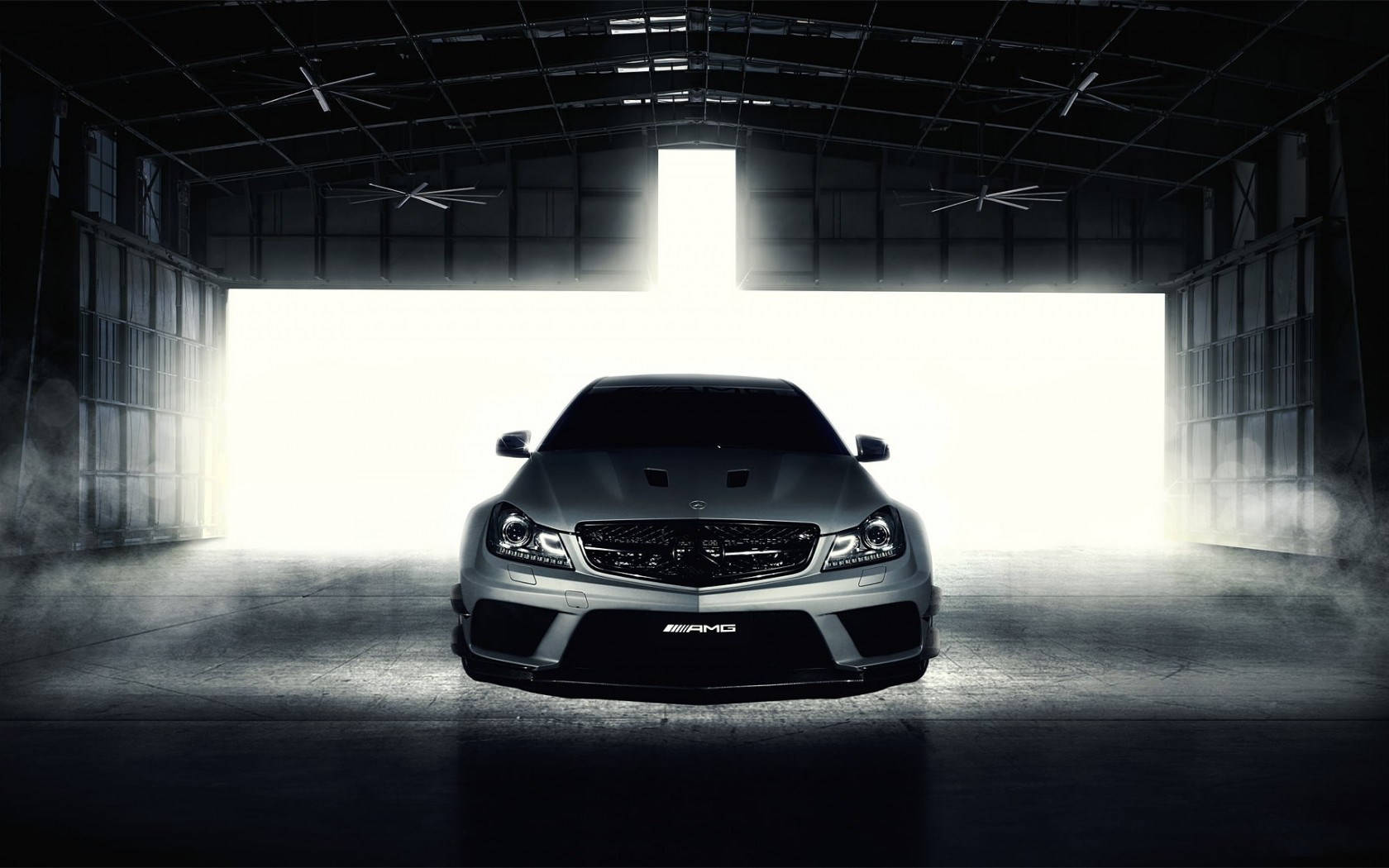 Mercedes Benz Amg 桌布 壁紙 — 一架時尚的銀色AMG跑車在黑暗的工業機庫中從後方被戲劇性地照亮，煙霧在其底座周圍旋轉。