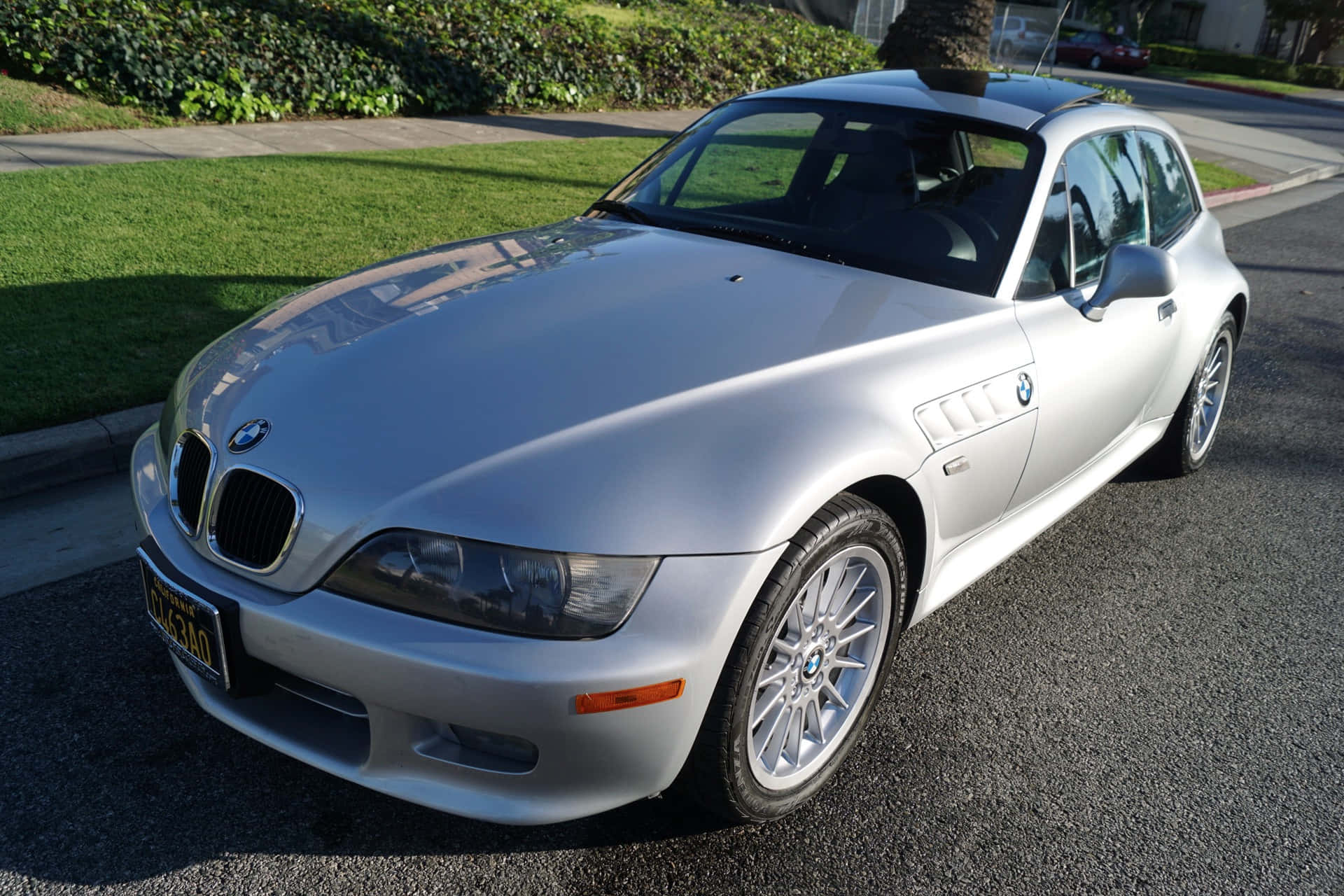 Bmw Z3 桌布 壁紙 — 一架時尚的銀色BMW Z3敞篷跑車停放在陽光明媚的住宅街道上，背景有綠草和樹籬。