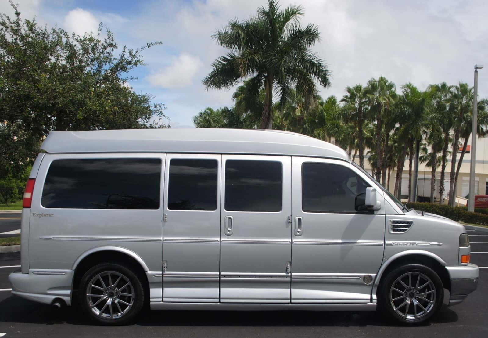 Gmc Savana 桌布 壁紙 — 一架時尚的銀色Ford Explorer Sport Trac停放在停車場，背景有棕櫚樹和多雲的天空。