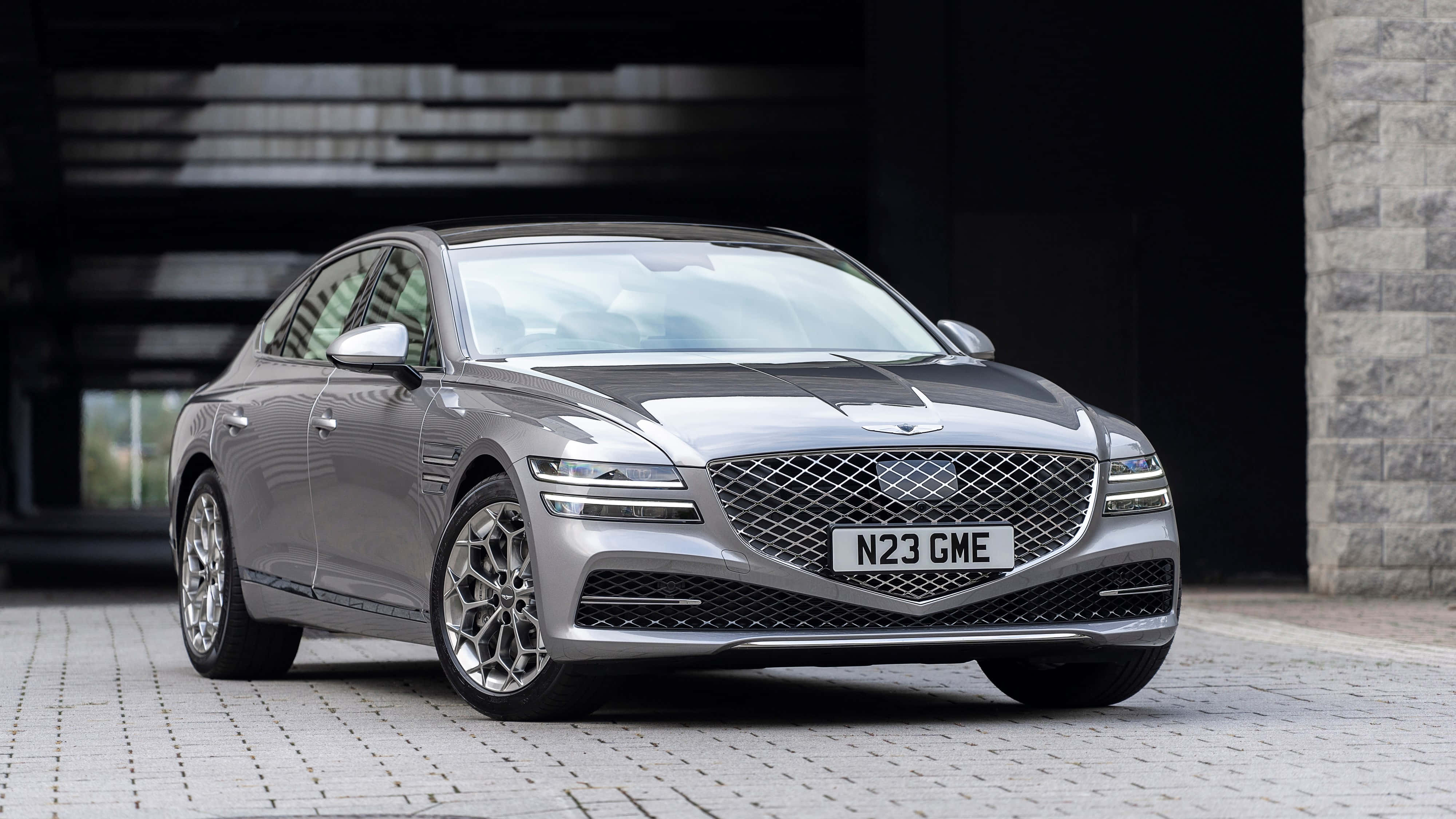 Genesis G80 桌布 壁紙 — 一架時尚的銀色Genesis G90豪華轎車停放在現代建築結構下的石頭車道上。