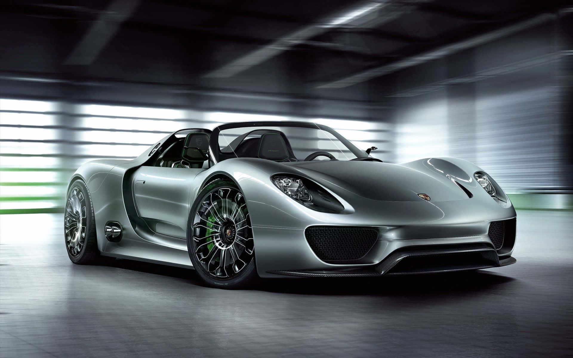 Coolest 桌布 壁紙 — 一架時尚的銀色保時捷918 Spyder跑車，帶有綠色點綴，停放在現代工業車庫中，背景呈現動態模糊效果。