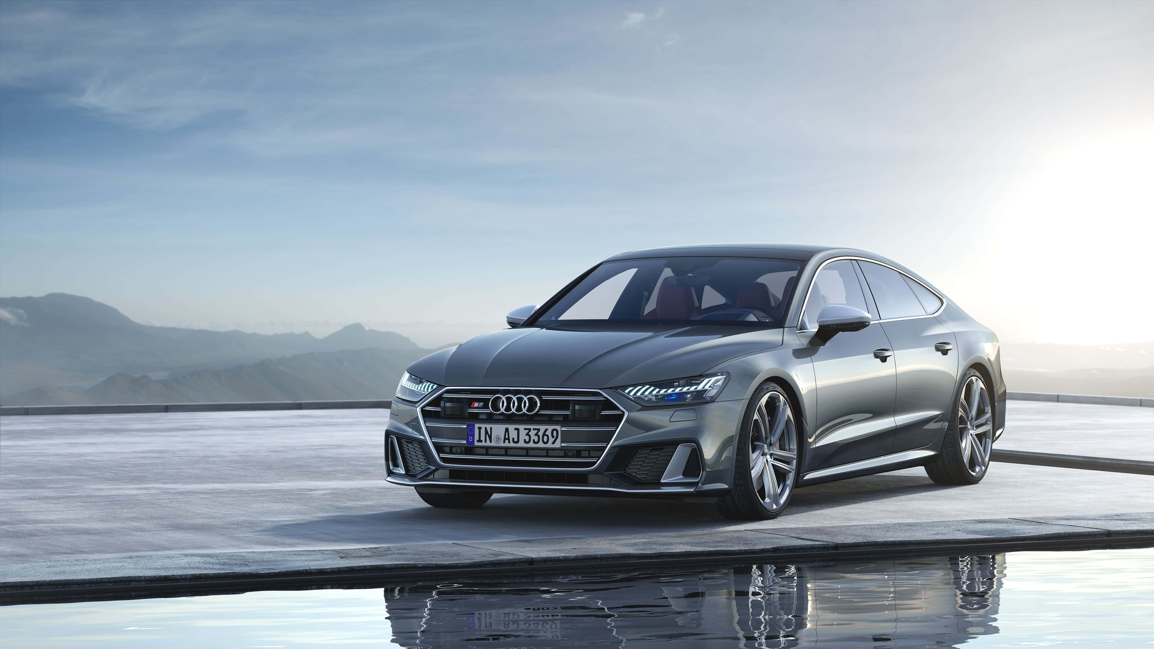 Audi S7 桌布 壁紙 — 一架時尚的銀色奧迪RS7 Sportback在柔和日光下，以山巒為背景，在濕潤平台上閃閃發光。