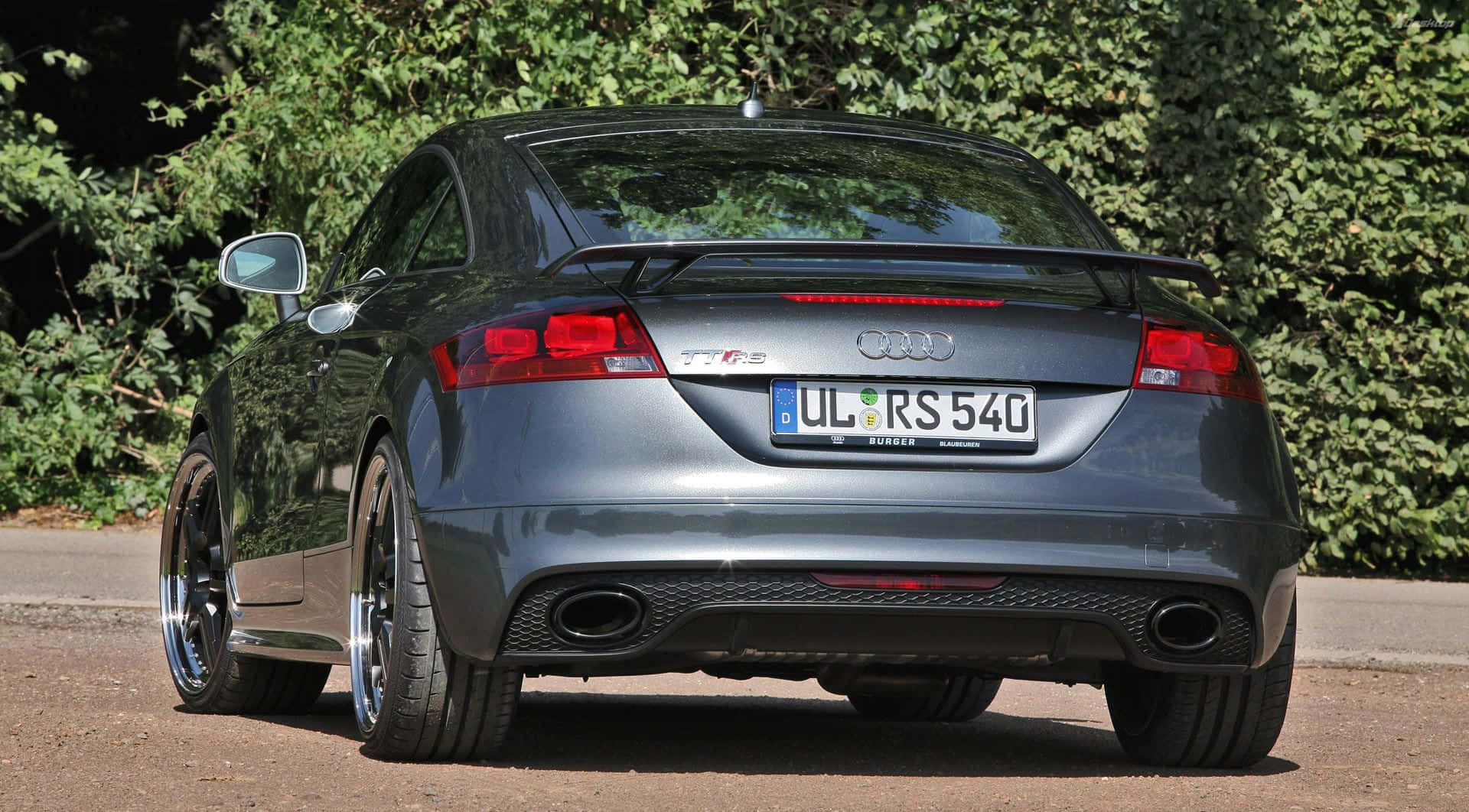 Audi Tt 桌布 壁紙 — 一架時尚的銀色奧迪TT RS跑車停泊在碎石路上，背景是茂密的綠色樹葉。