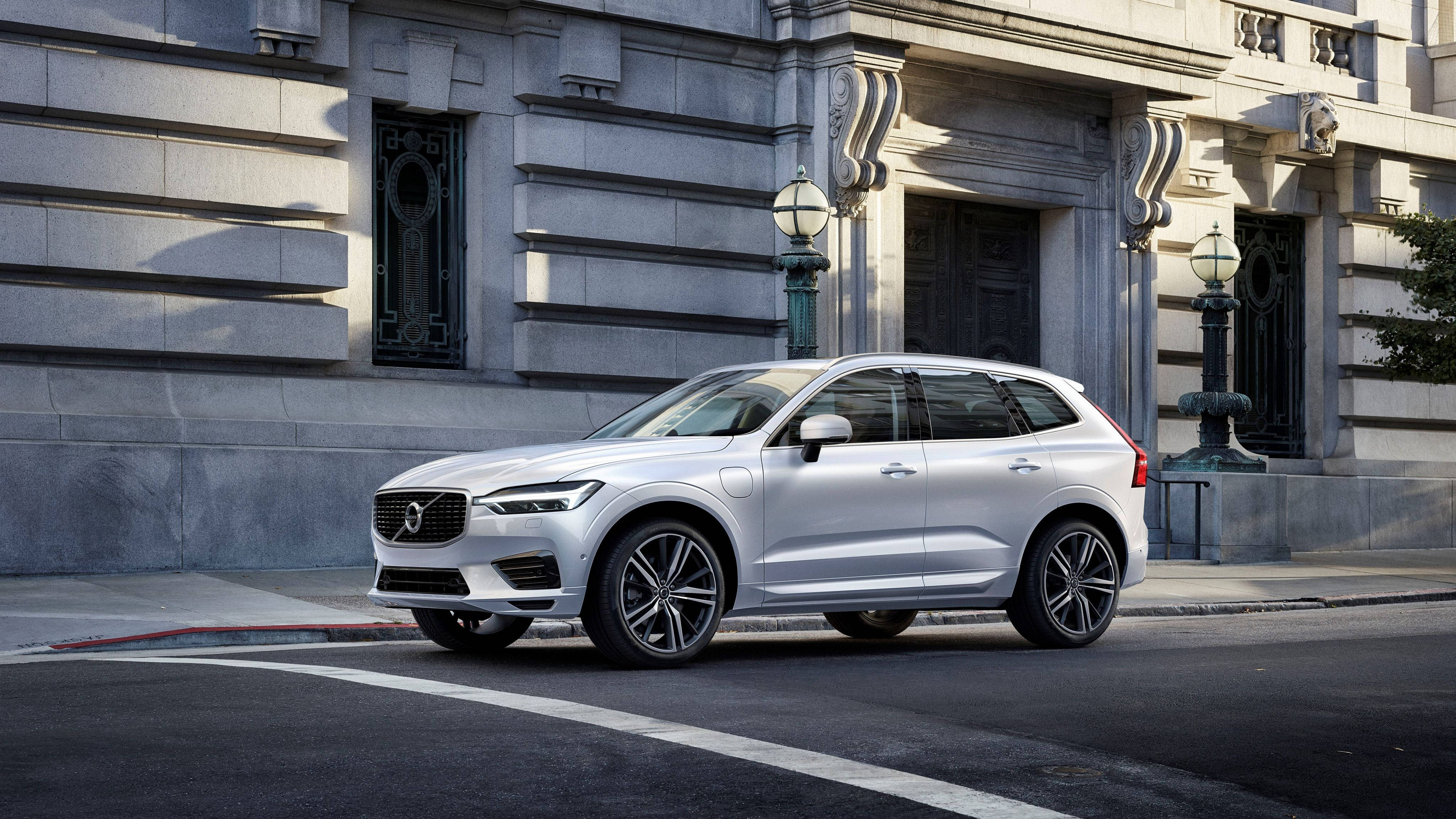 Volvo 桌布 壁紙 — 一架時尚的銀色富豪SUV停泊在城巿街道上，旁邊是一座帶有華麗細節的宏偉石建築。