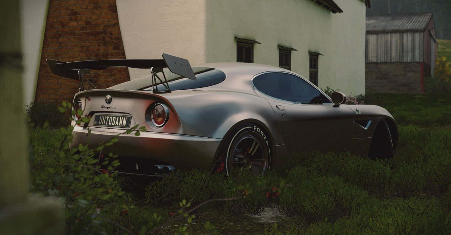 Alfa Romeo 8c Competizione 桌布 壁紙 — 一架時尚的銀色愛快羅密歐賽車，帶有大型尾翼，被遺棄在白色建築物旁邊雜草叢生的草地上。