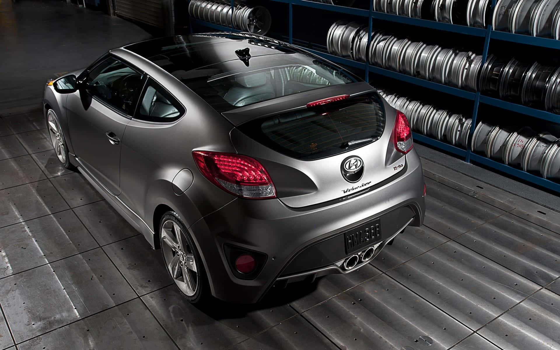 Hyundai Veloster 桌布 壁紙 — 一架時尚的銀色現代Veloster跑車停放在倉庫中，後面有輪胎架。