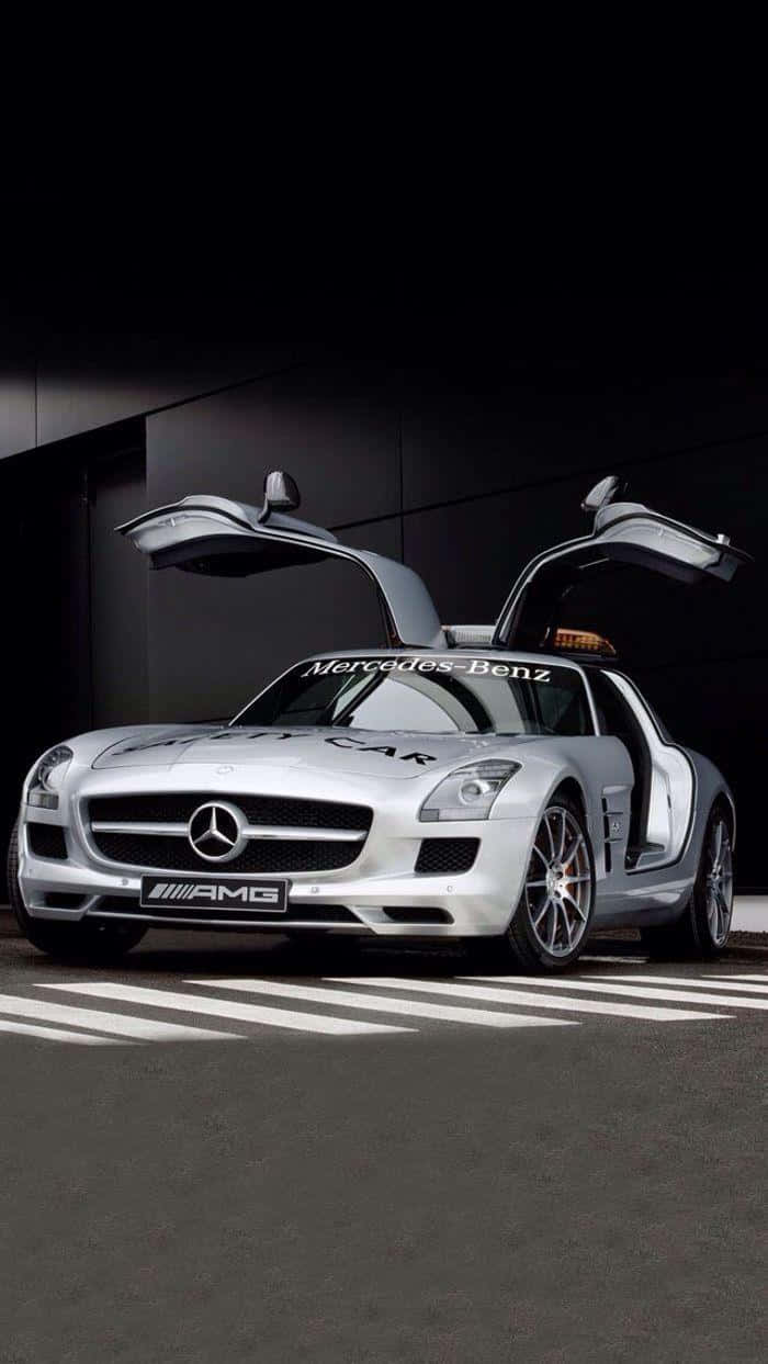 Safety Car 桌布 壁紙 — 一架時尚的銀色賓士SLS AMG安全車，鷗翼車門打開，停在有白色標線的深色瀝青路上，在戲劇性的工作室燈光下。
