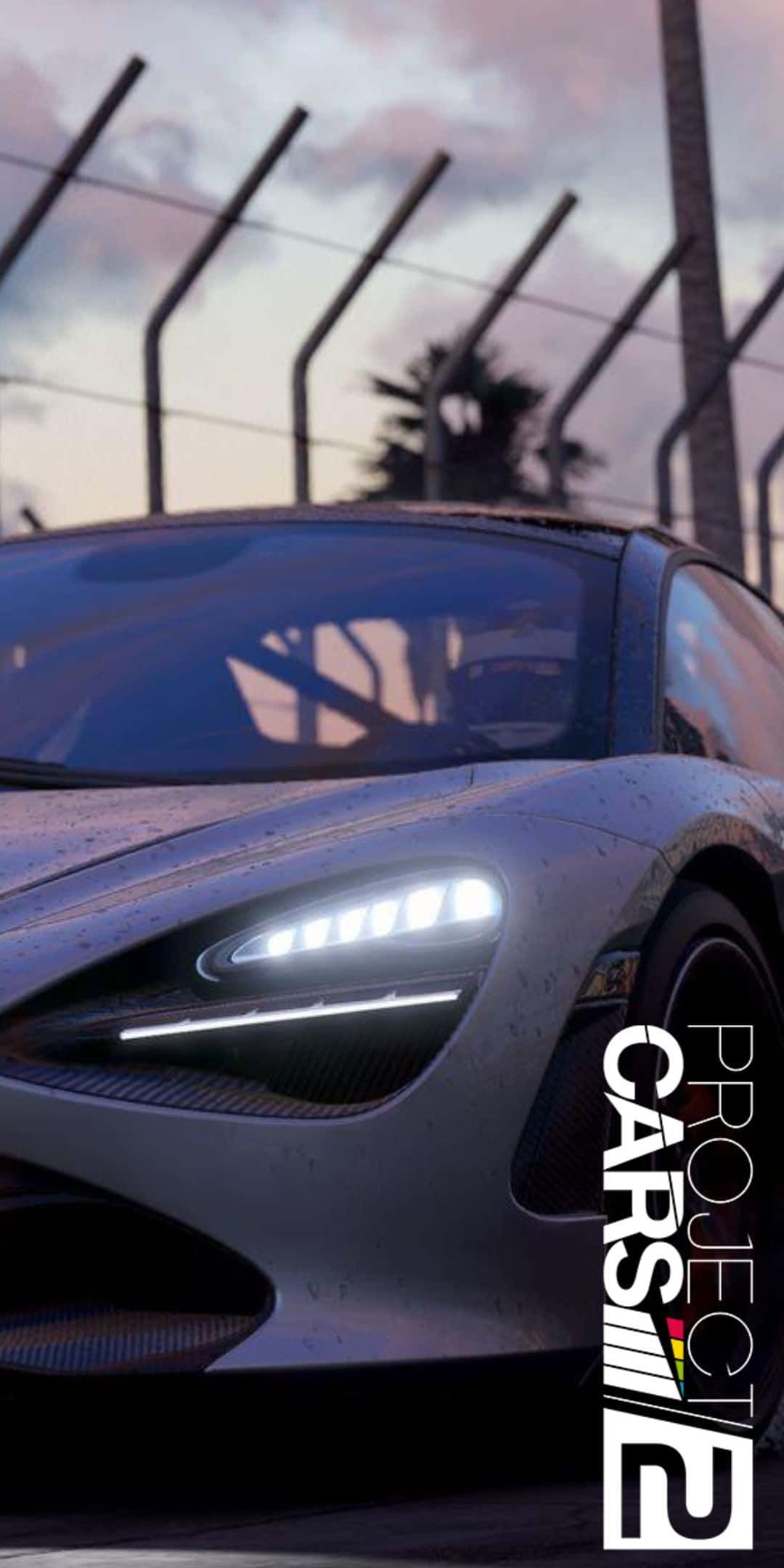 Pixel 3 Project Cars 2 桌布 壁紙 — 一架時尚的銀色賽車，車頭燈閃爍，停在黃昏的賽道上，背景有棕櫚樹和圍欄。