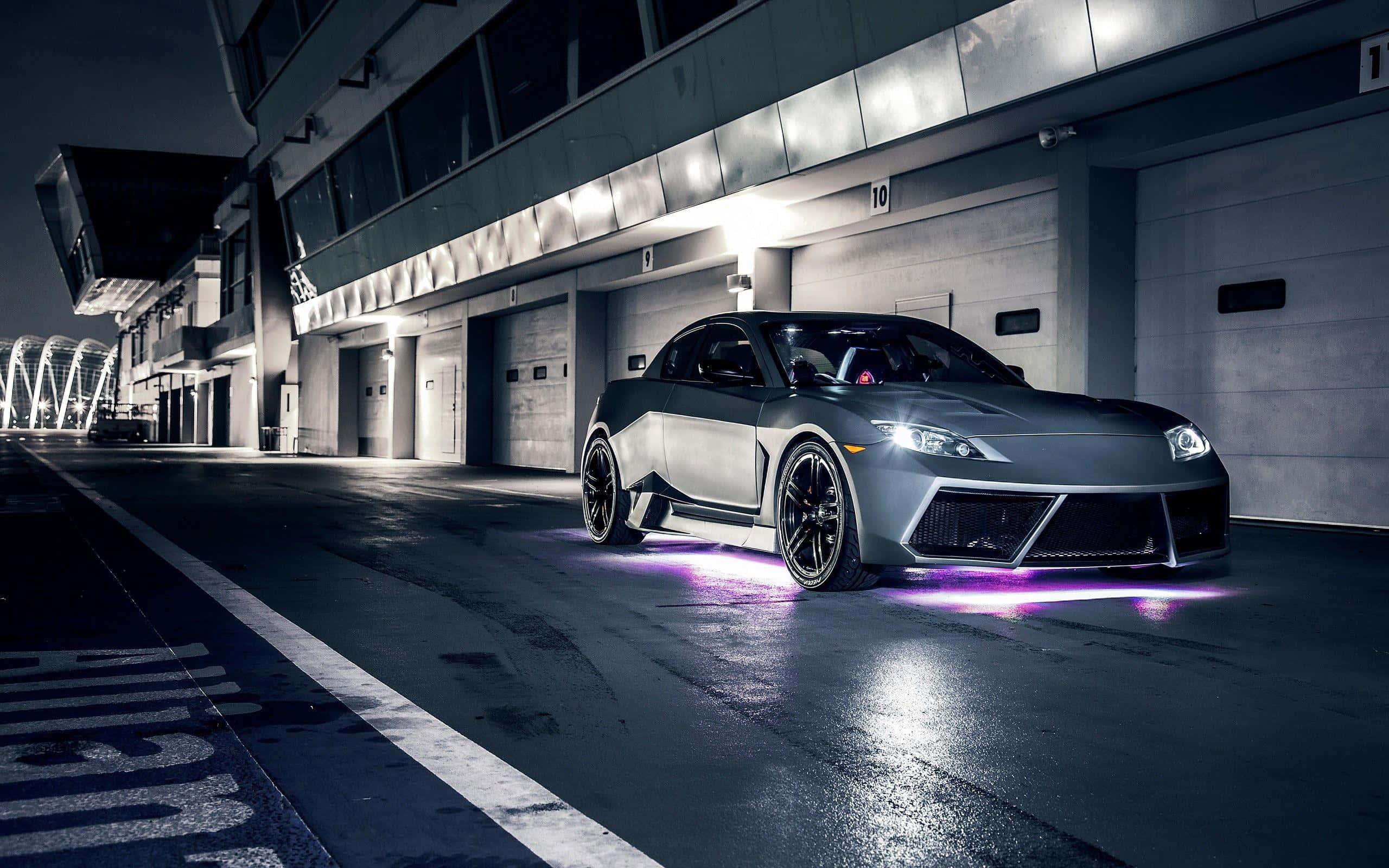 Mazda Rx-8 桌布 壁紙 — 一架時尚的銀色跑車，帶有發光的紫色底盤燈，夜晚停放在現代車庫中。
