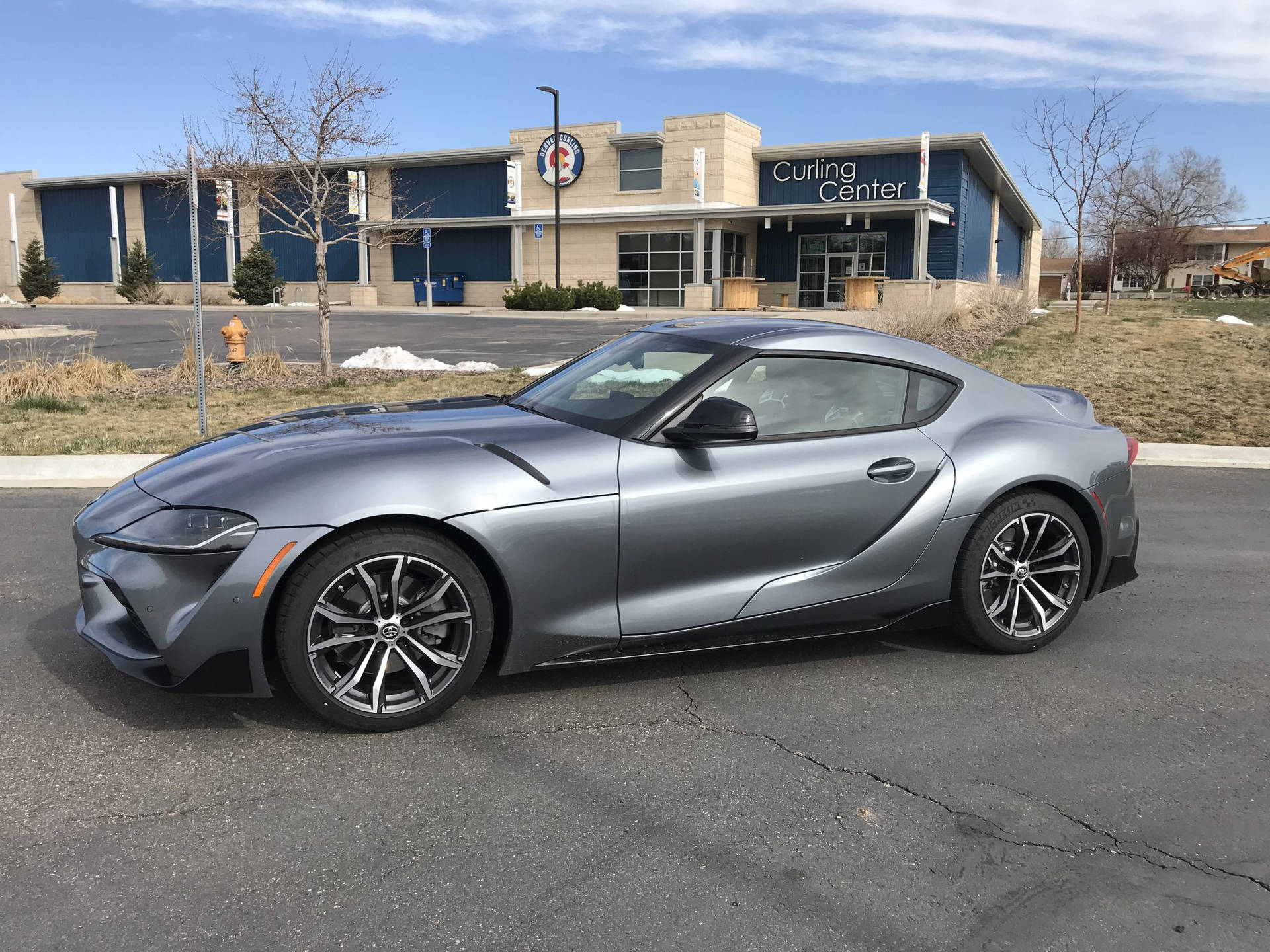 冬日，銀色跑車停放在冰壺中心前。 — Toyota Supra Mk4 壁紙
