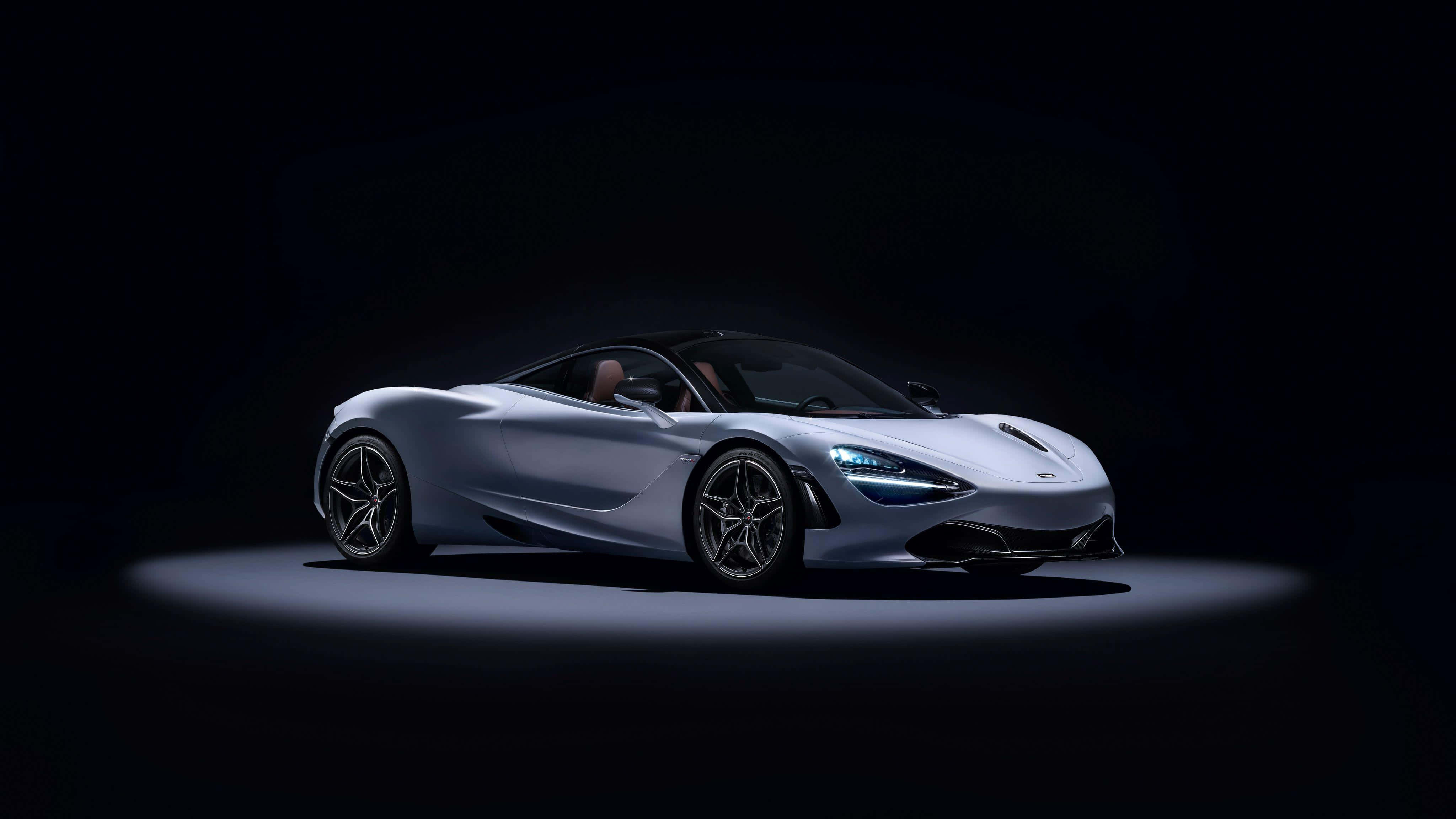 麥拉倫 720S 桌布 壁紙 — 一架時尚的銀色跑車在單一聚光燈下，在漆黑的攝影棚背景中閃耀。