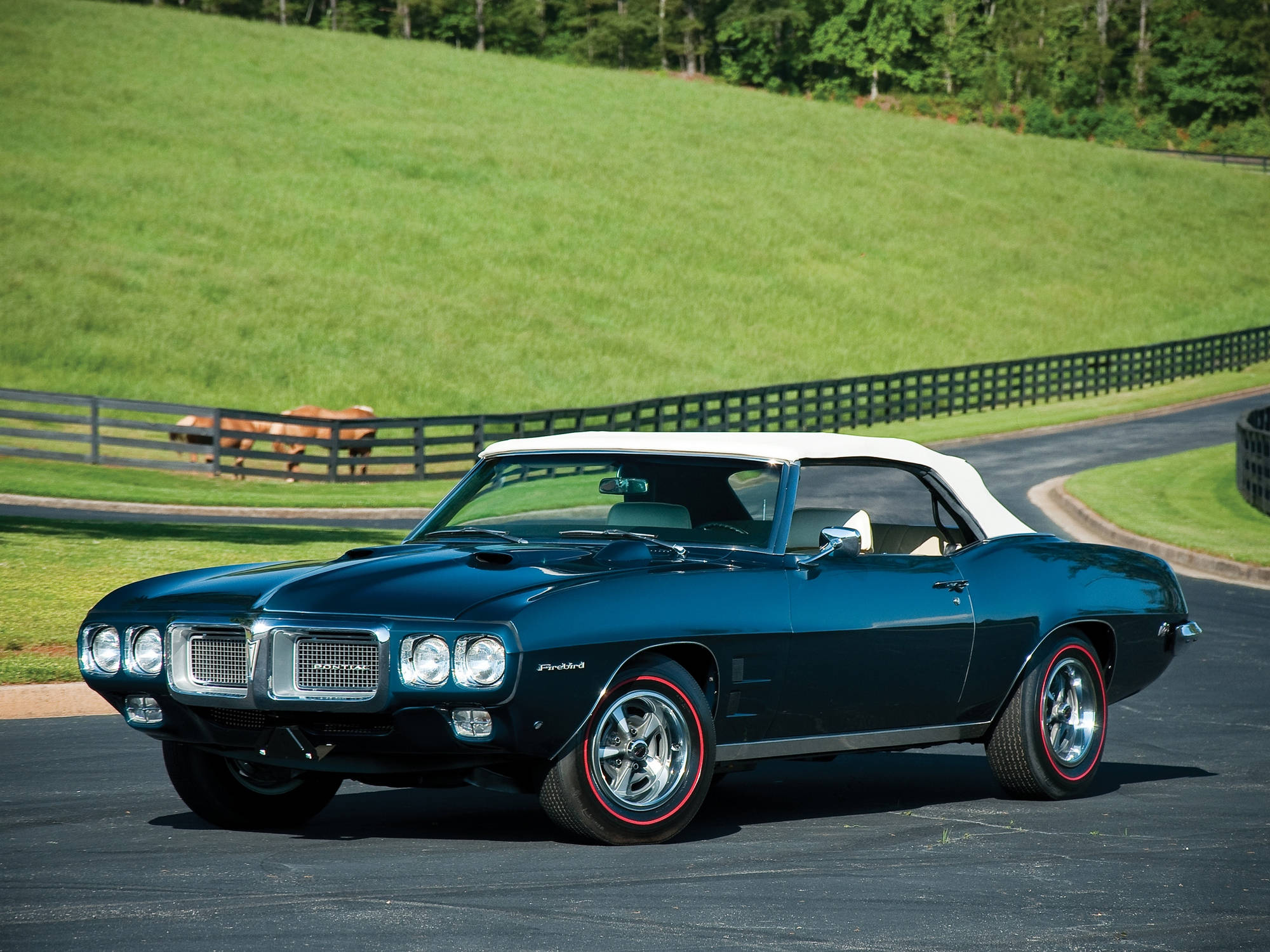 Pontiac 桌布 壁紙 — 一架時尚的青綠色經典敞篷車，白色車頂，停泊在鋪砌道路上，旁邊是翠綠的山丘，籬笆後有一匹馬在吃草。