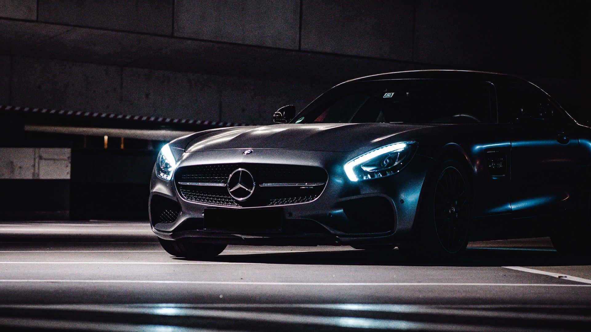 桌布 壁紙 — 一架時尚的黑色 Mercedes-AMG GT 跑車在昏暗的地下停車場中，在霓虹燈下閃耀。