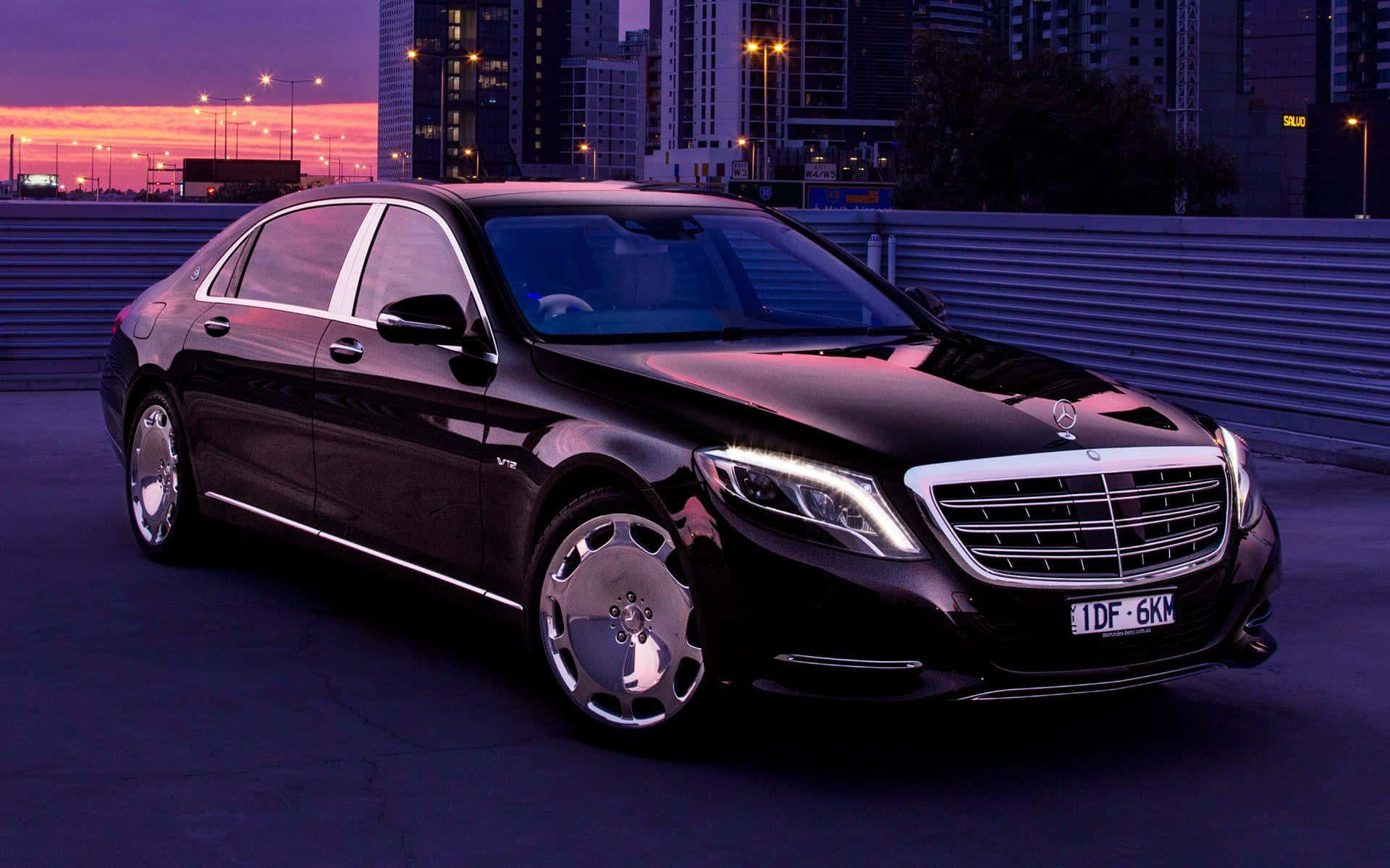 Maybach 桌布 壁紙 — 一架時尚的黑色 Mercedes-Maybach S600 停放在屋頂上，背景是暮色中充滿活力的紫色和橙色城市天際線。