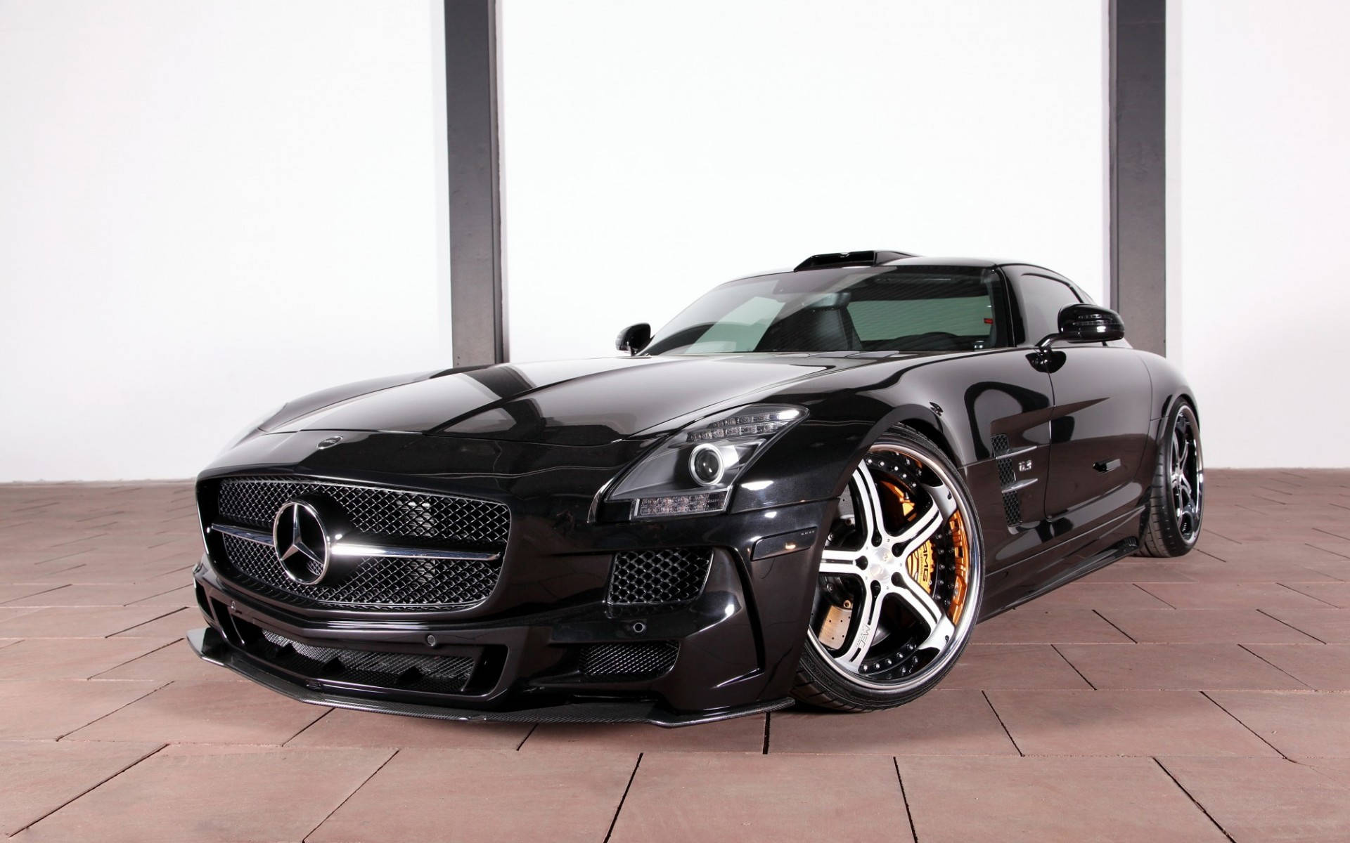 跑車 桌布 壁紙 — 一架時尚的黑色 Mercedes SLS AMG 跑車，配備金色制動卡鉗和定制輪圈，在鋪有瓷磚地板和白色牆壁的簡約工作室中展示。
