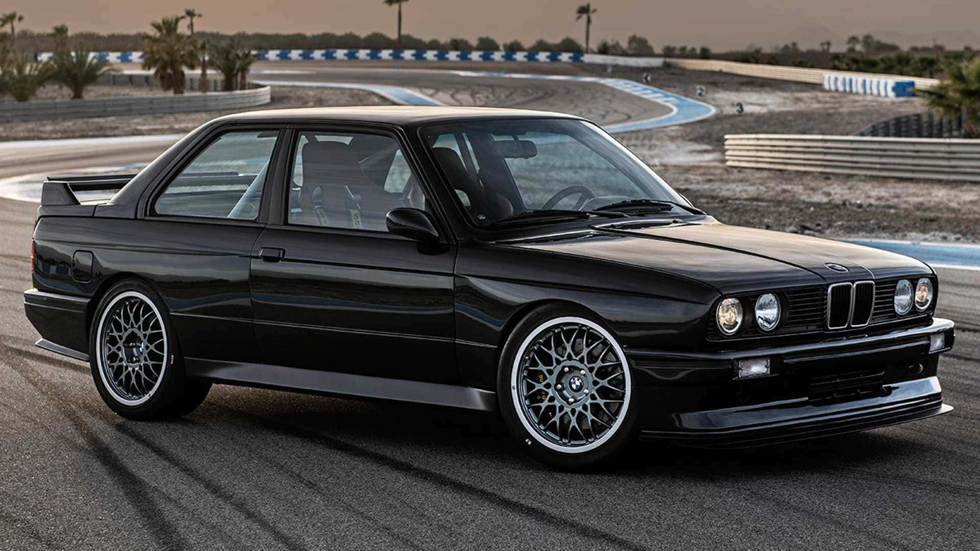 BMW 動圖 桌布 壁紙 — 一架時尚的黑色BMW E30雙門轎跑車停在沙漠賽道上，背景有棕櫚樹和藍白色路緣。