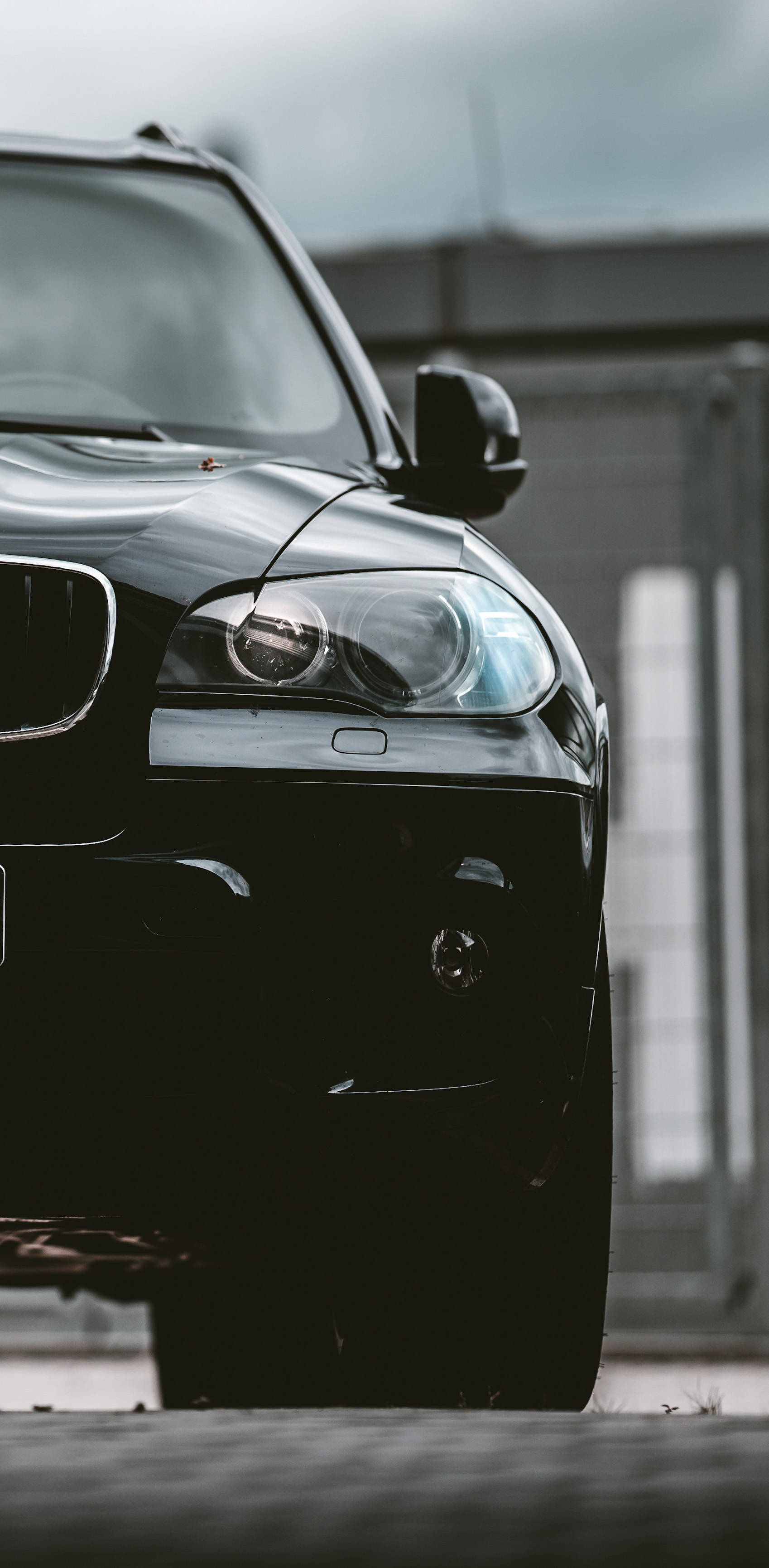 Black Bmw 桌布 壁紙 — 一架時尚的黑色BMW SUV在陰天之下，以其光澤表面和銳利車頭燈主導畫面。