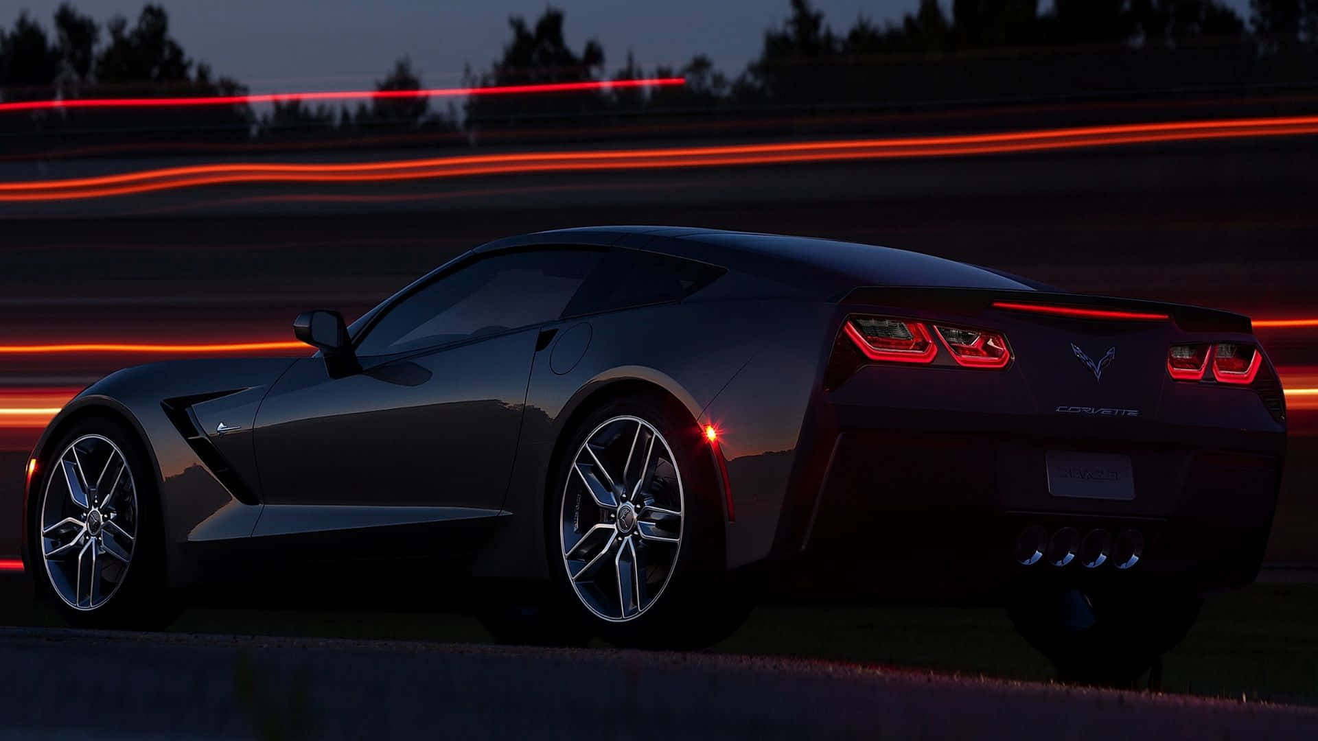 Chevrolet Corvette Stingray 桌布 壁紙 — 一架時尚的黑色Corvette跑車在黃昏時滑行，鮮豔的紅色光軌在黑暗的賽道上向後延伸。
