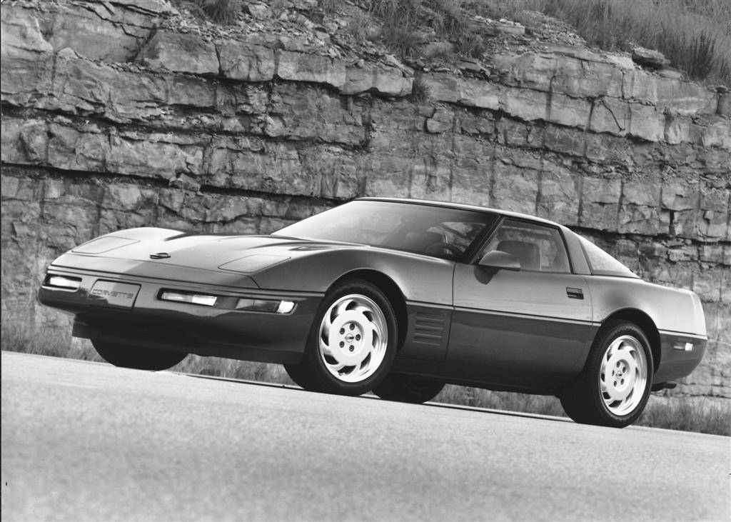 corvette 桌布 壁紙 — 一架時尚的黑色Corvette跑車停泊在單色調的崎嶇石崖旁邊的道路上。