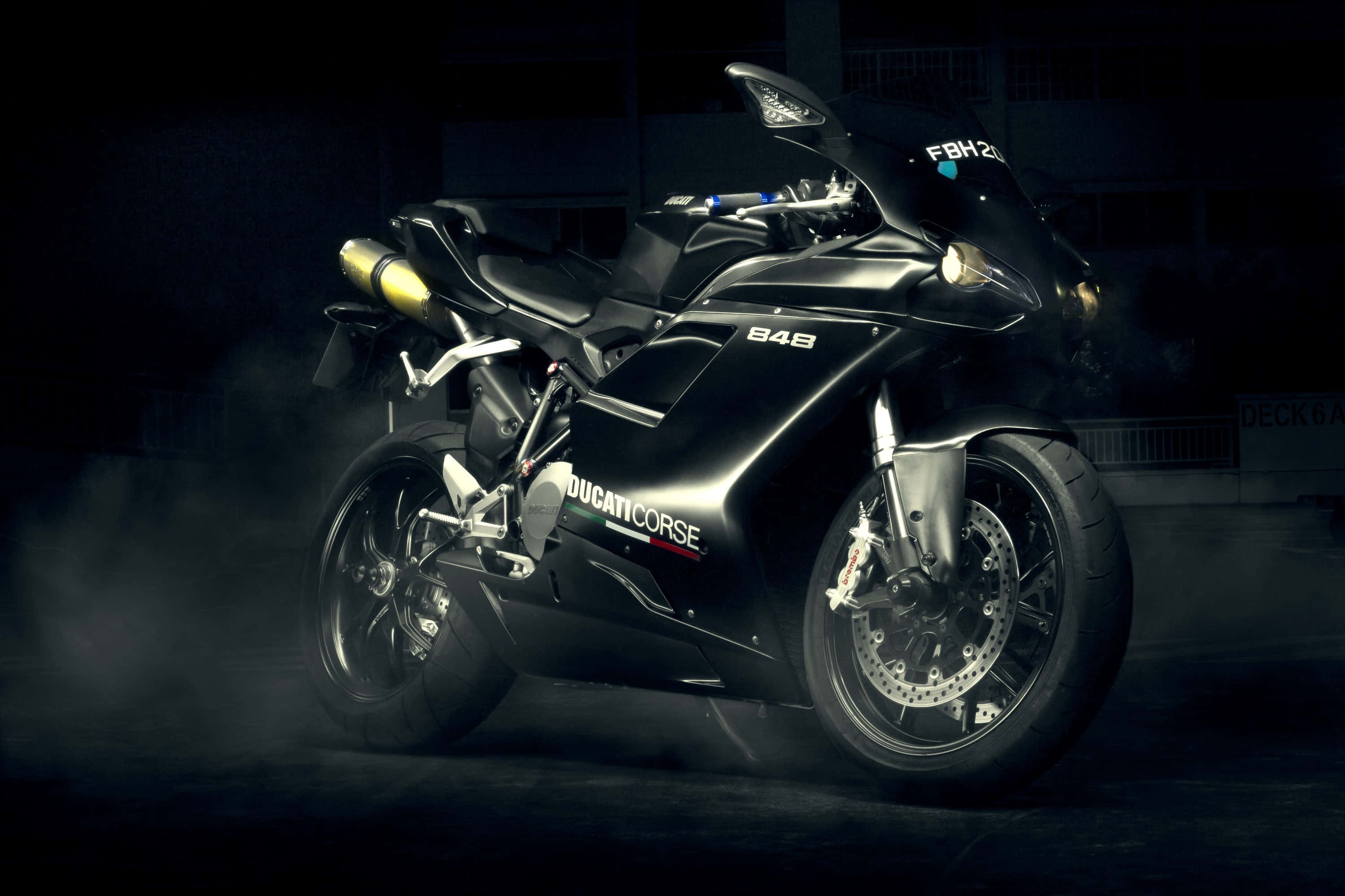 Superbike 桌布 壁紙 — 一架時尚的黑色Ducati Corse摩托車在昏暗車庫中，於戲劇性燈光下發光，煙霧在輪胎周圍旋轉。