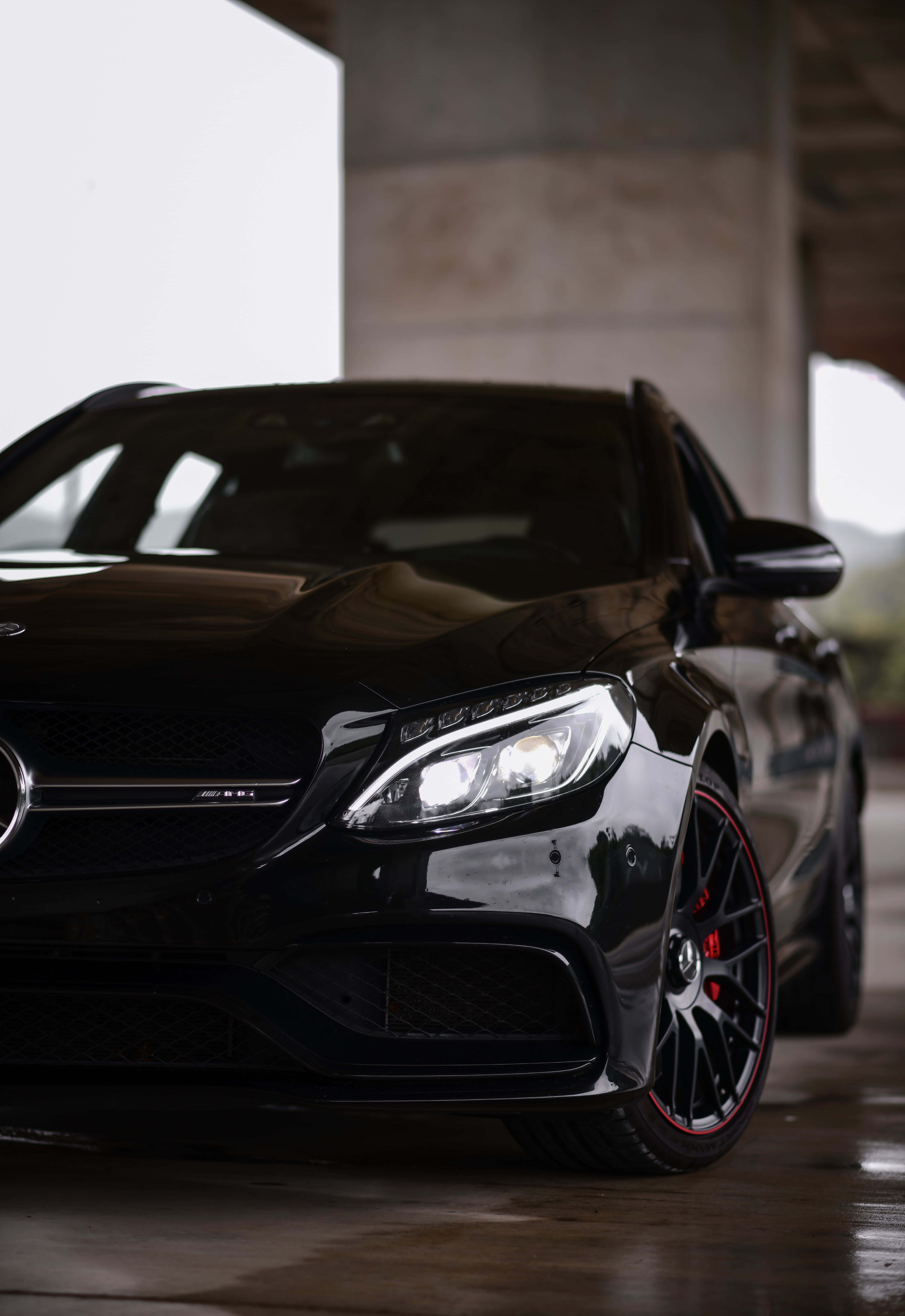 桌布 壁紙 — 一架時尚的黑色Mercedes-AMG跑車，紅色制動卡鉗在混凝土車庫的柔和燈光下閃閃發光。