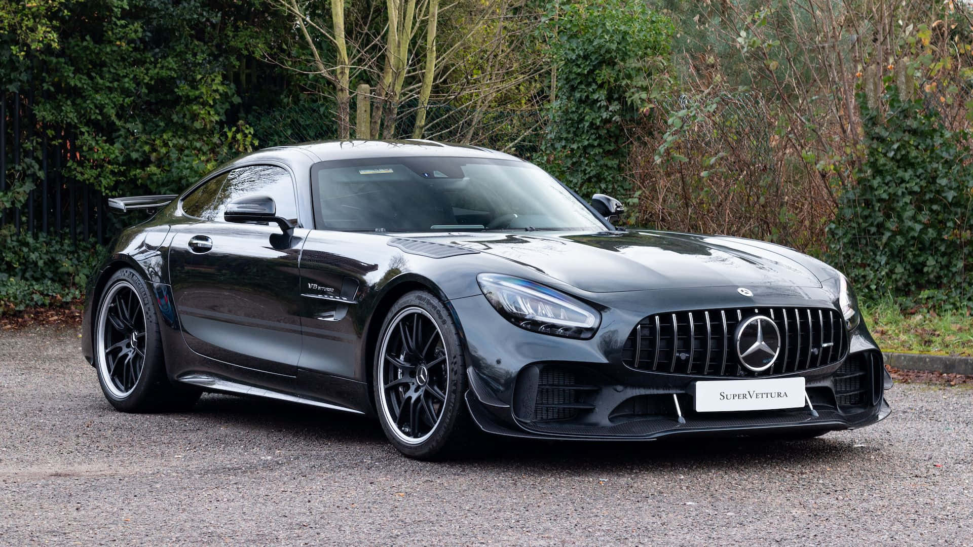 汽車 桌布 壁紙 — 一架時尚的黑色Mercedes-AMG GT Black Series超級跑車停在碎石上，背景有綠色的灌木叢。