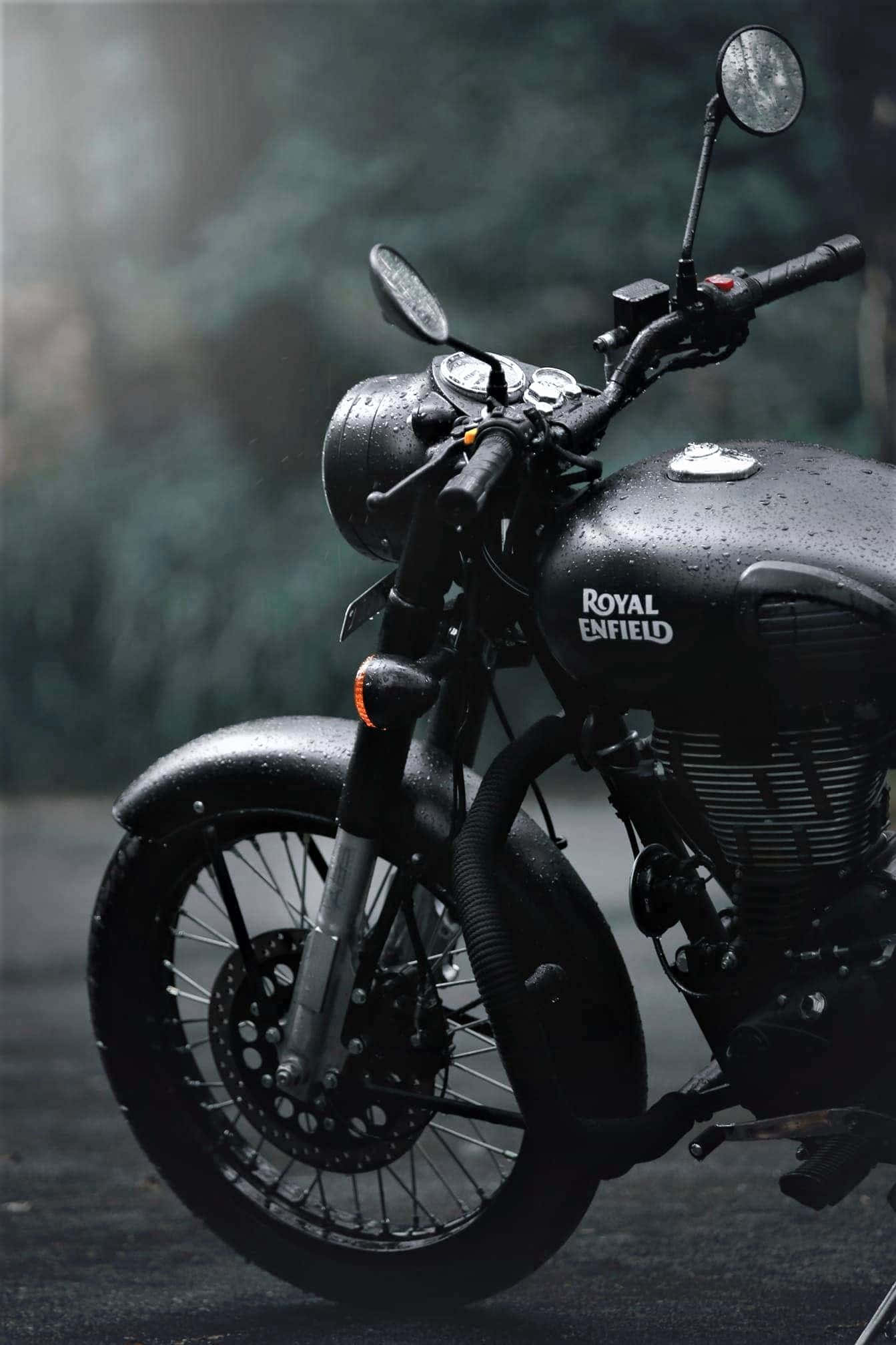 Royal Enfield Bullet 桌布 壁紙 — 一架時尚的黑色Royal Enfield機車在霧氣籠罩的森林背景下閃爍著雨滴。