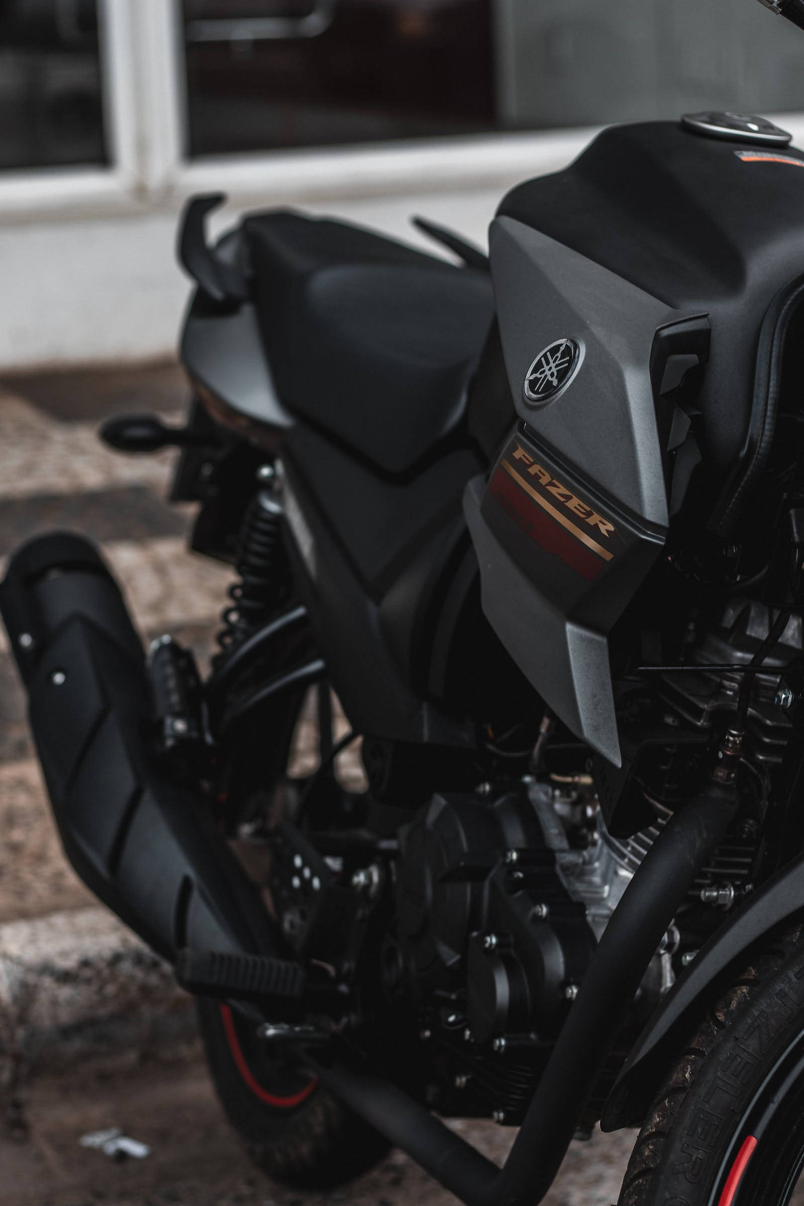 機車 桌布 壁紙 — 一架時尚的黑色Yamaha Fazer機車停在石頭表面上，背景是模糊的建築物。