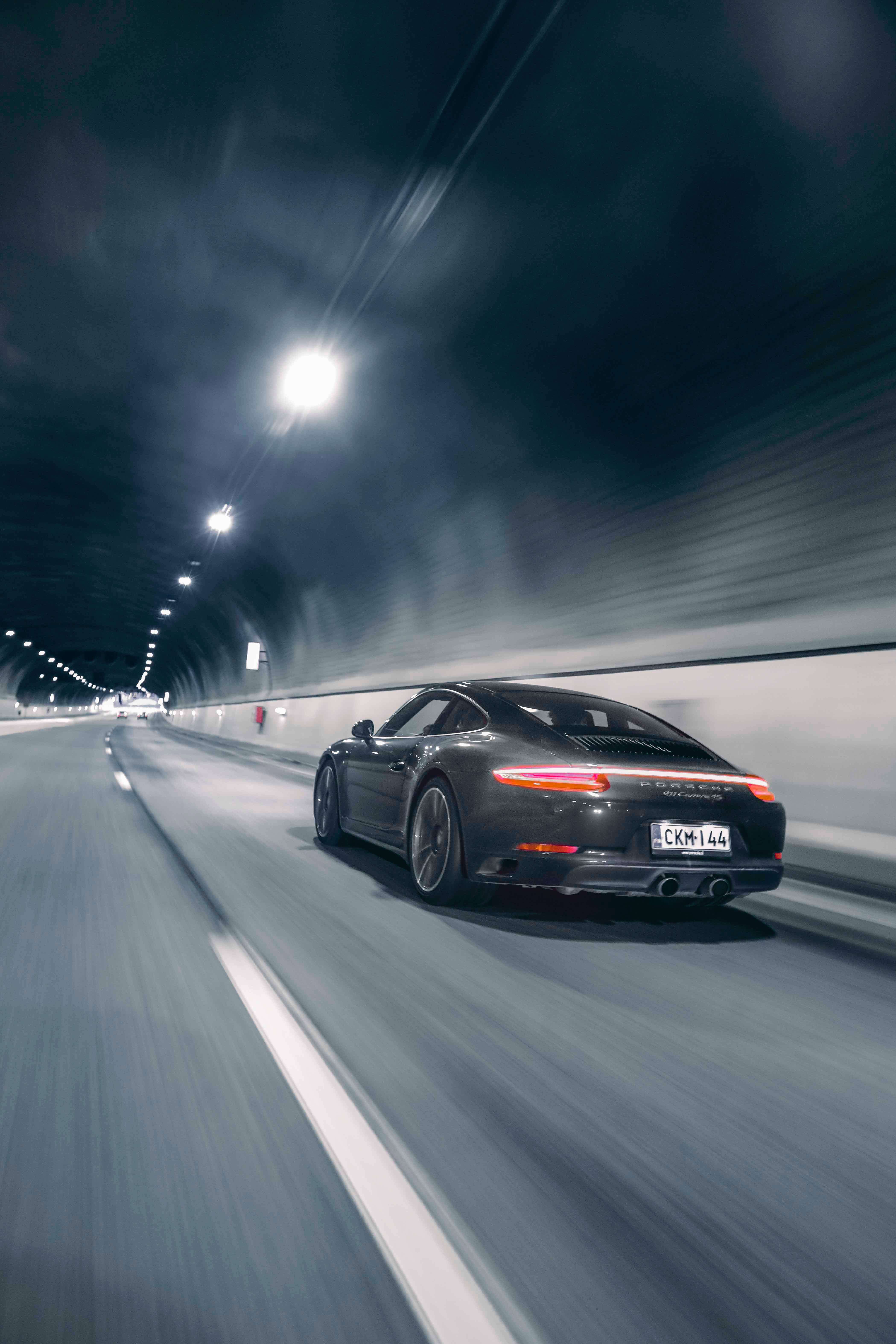 speeding car 桌布 壁紙 — 一架時尚的黑色保時捷911在燈光昏暗的隧道中疾馳，留下動態模糊的痕跡。