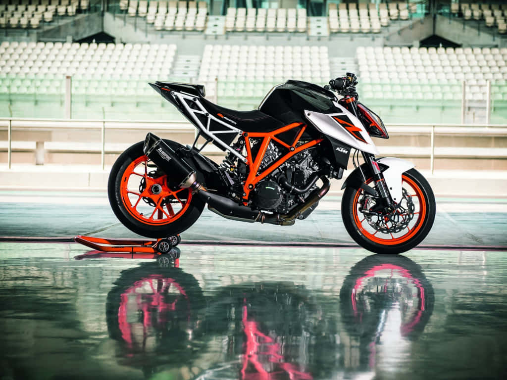 Superbike 桌布 壁紙 — 一架時尚的黑色和橙色KTM機車停在空蕩蕩的體育館內反射著濕滑的賽道上。