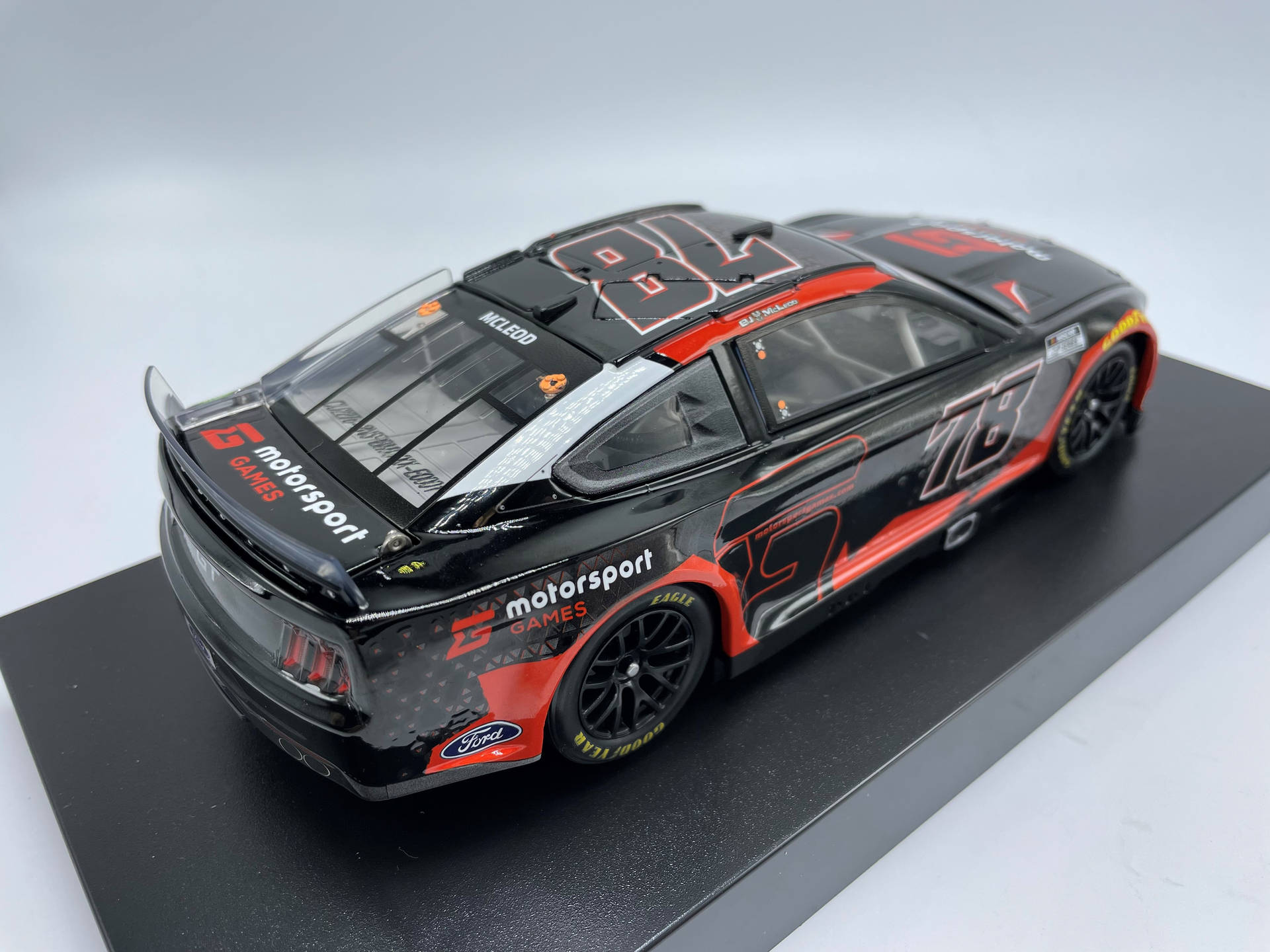Black 桌布 壁紙 — 一架時尚的黑色和紅色 #78 福特 NASCAR 賽車模型，帶有詳細的貼花，放置在黑色展示架上，背景是乾淨的白色。