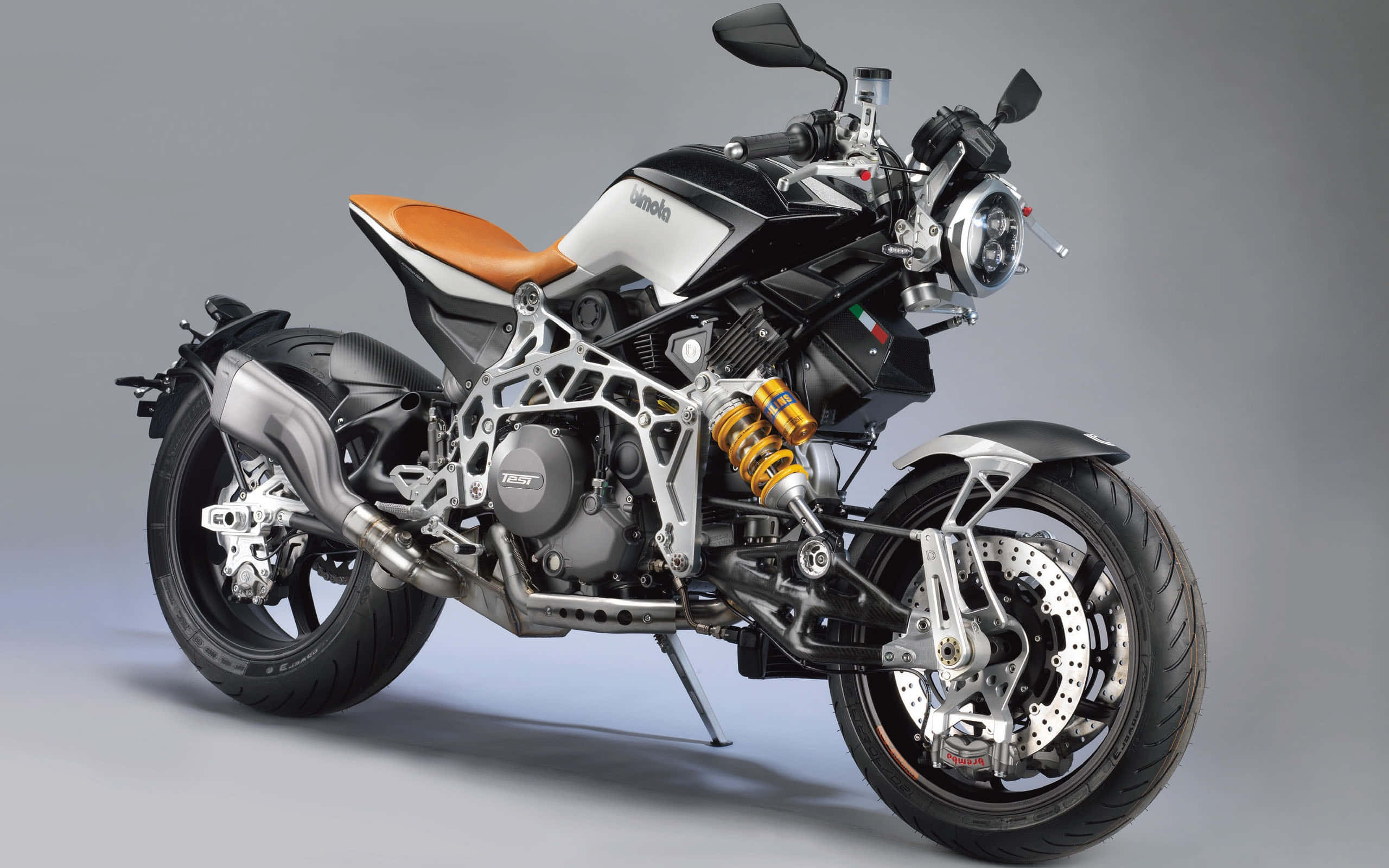 Superbike 桌布 壁紙 — 一架時尚的黑色和銀色摩托車，配備橙色座椅和金色懸掛，矗立在工作室的灰色地板上。